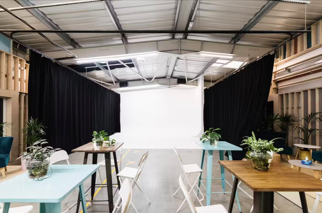 Versatile event space with white backdrop, ideal for presentations and workshops.
