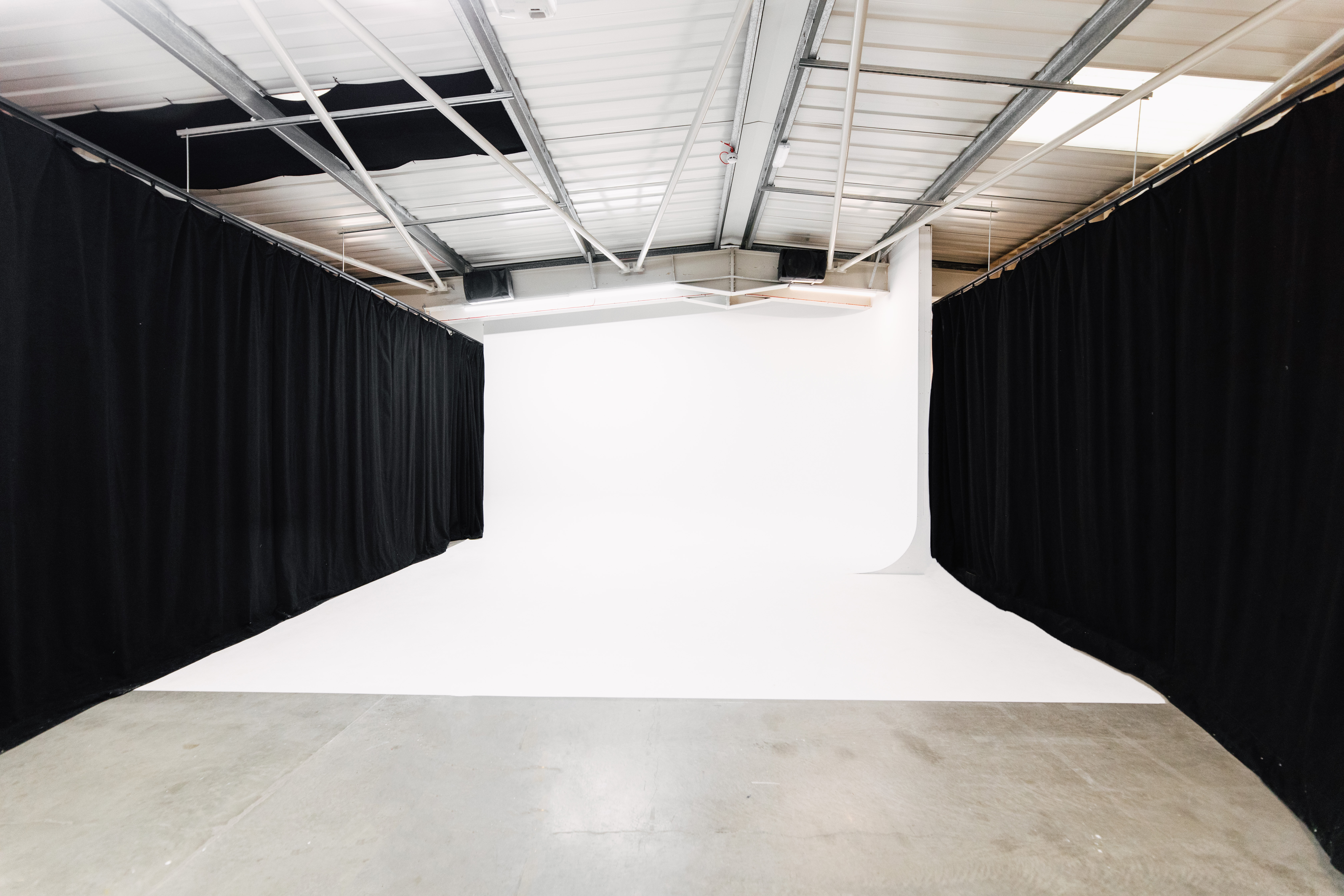 Versatile event space with white backdrop, ideal for presentations and photo shoots.