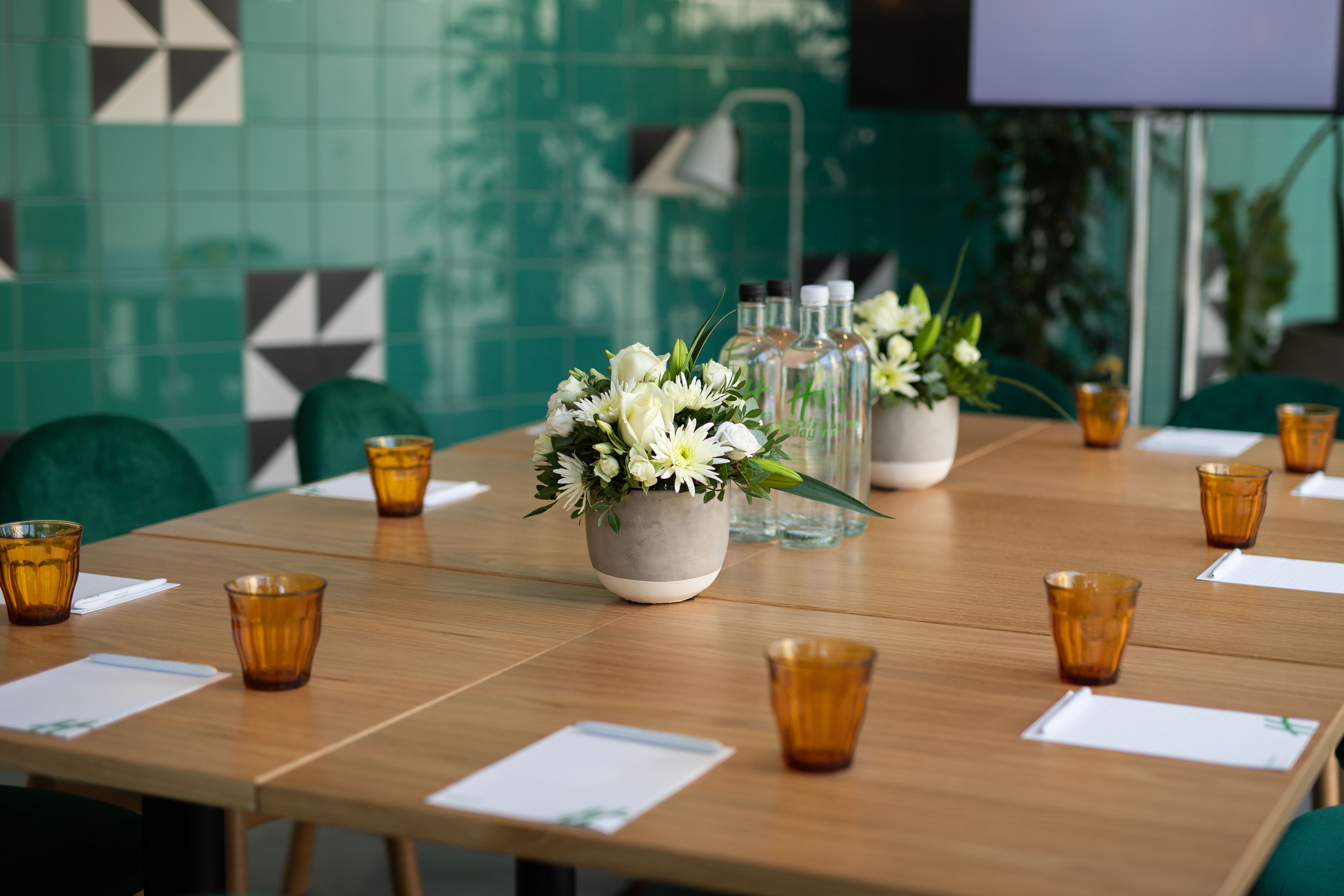Green Room at Holiday Inn London Whitechapel, modern meeting setup with fresh flowers.