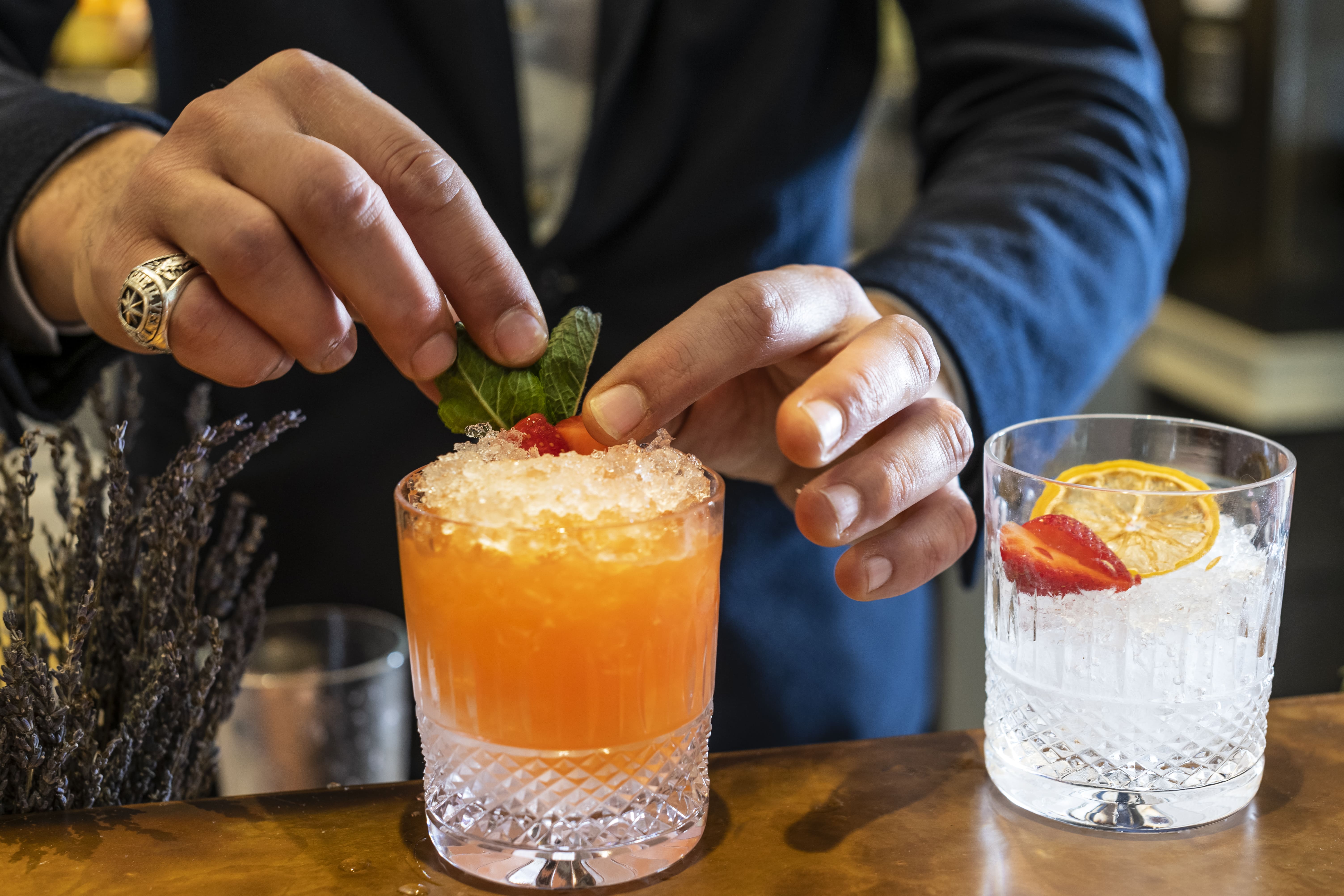 Bartender garnishing vibrant cocktail at Sloane Place Bar for event catering.