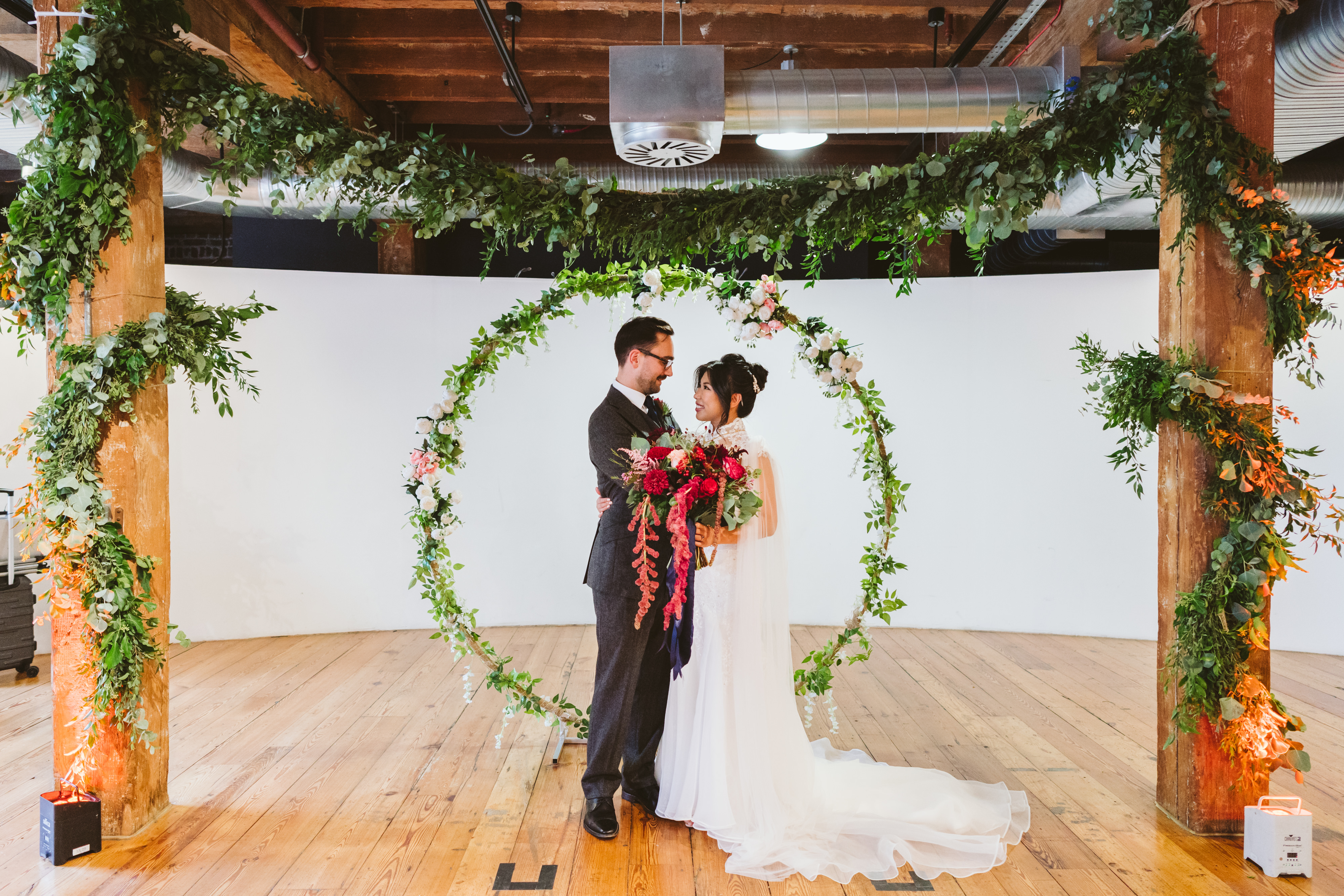 Wedding ceremony setup under floral arch at Rum Store, London Museum Docklands.