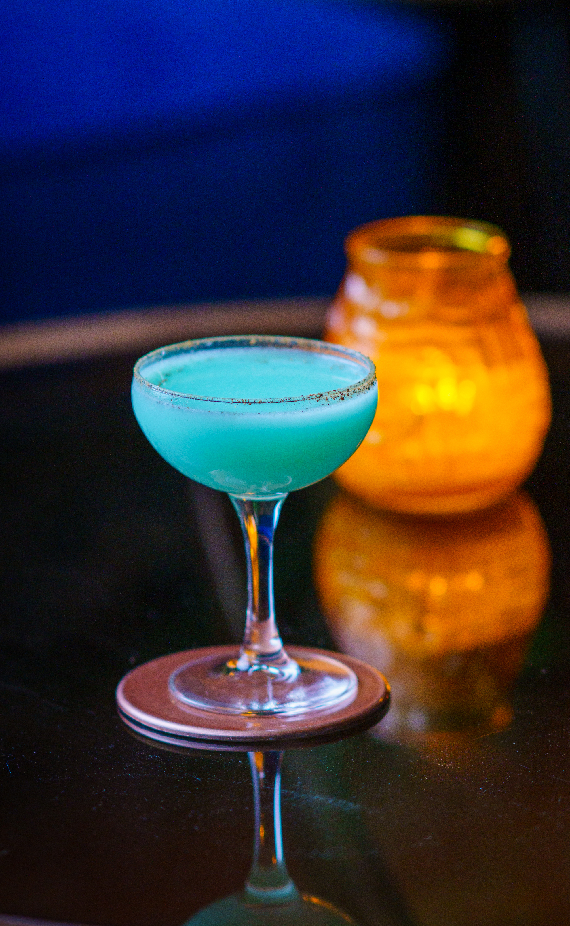 Vibrant blue cocktail in coupe glass at Trailer Happiness for networking events.