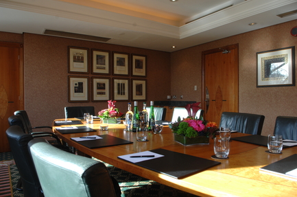 Boardroom meeting room with polished wooden table, ideal for corporate events and presentations.