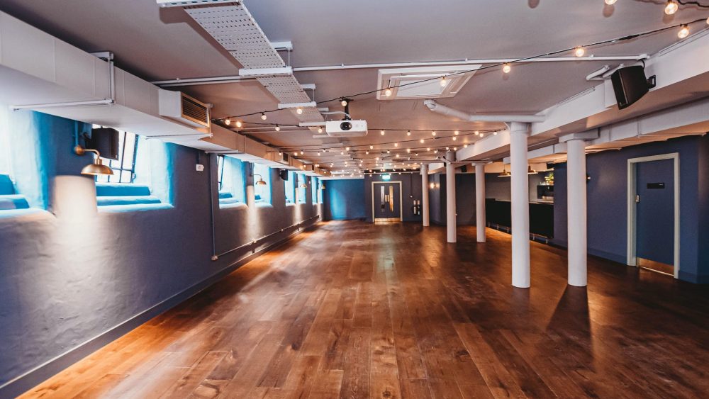 Versatile event space at The Storehouse, featuring polished wooden floors and ambient lighting.