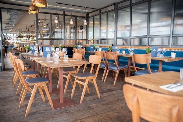 Modern restaurant interior with wooden tables, ideal for meetings and events.
