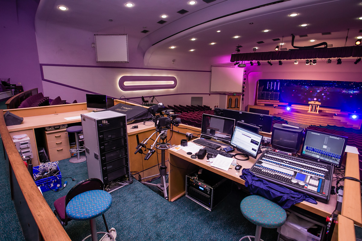 Event control room with screens and sound equipment for live presentations.