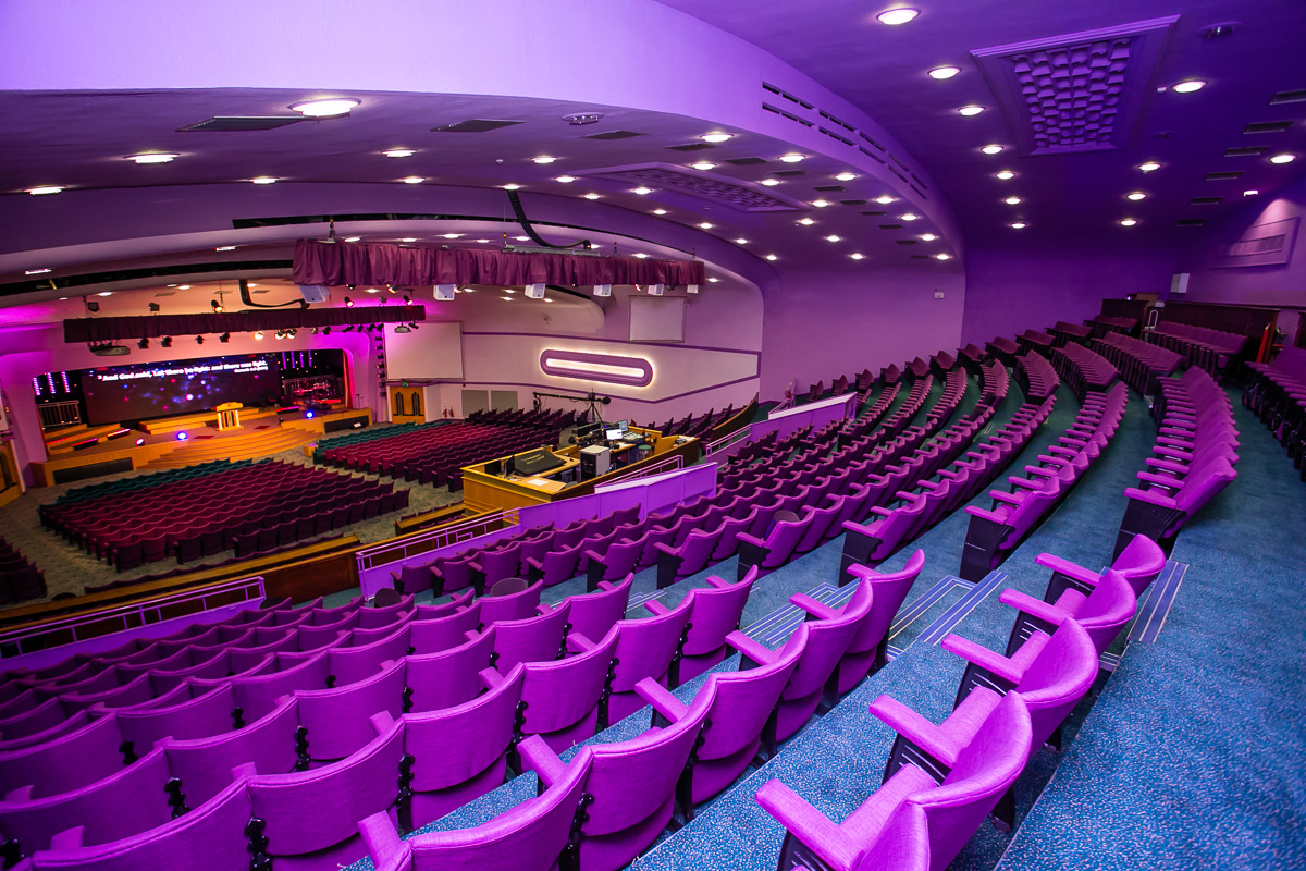 Spacious auditorium with purple seating, ideal for conferences and events.