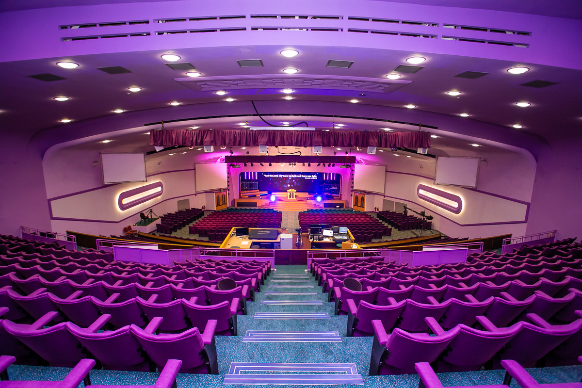Spacious Gateway House auditorium with tiered seating and vibrant purple lighting for events.