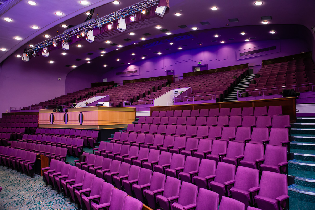 Spacious purple auditorium with tiered seating for conferences and seminars.