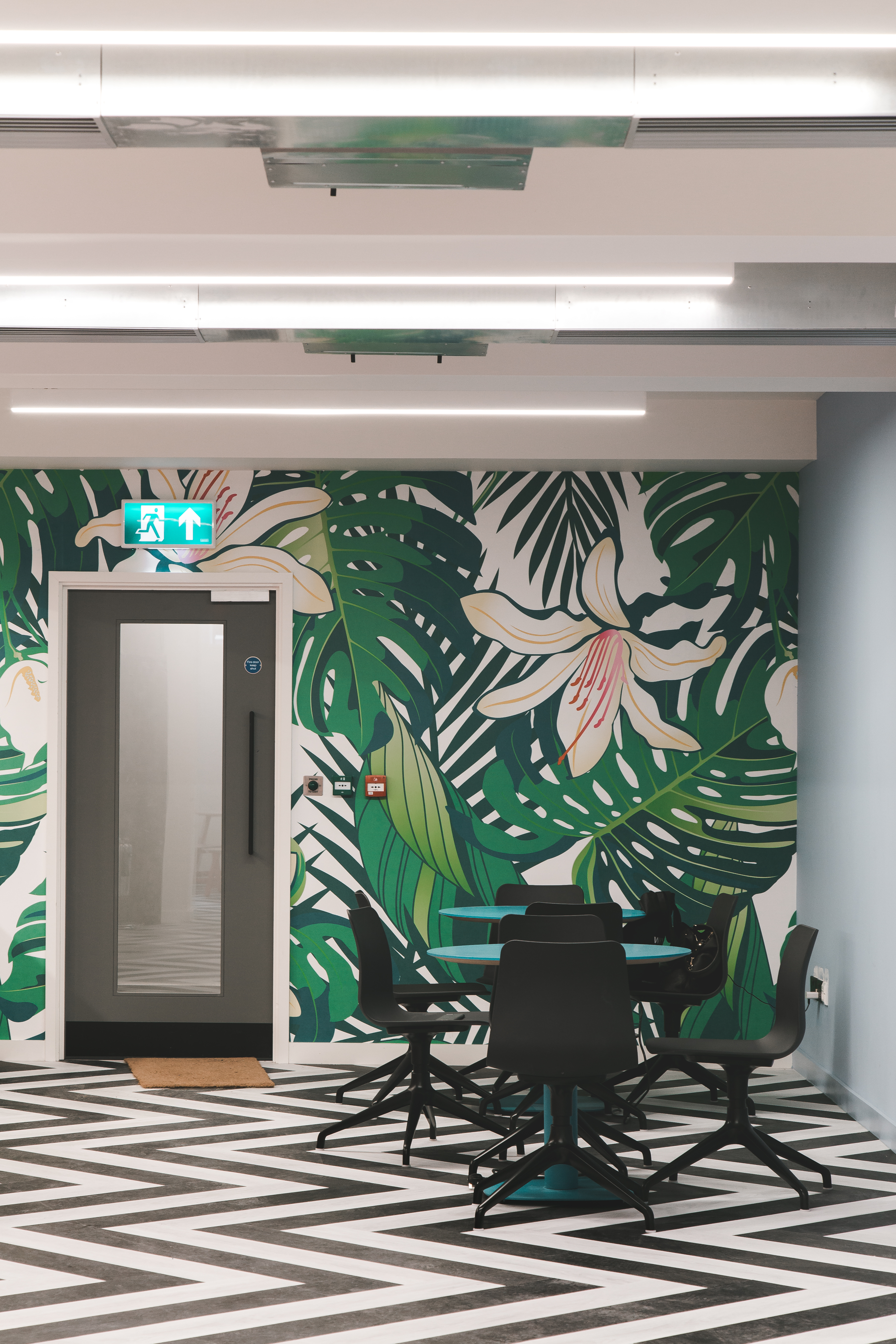 Vibrant meeting space with tropical mural at Huckletree Ancoats for events and gatherings.