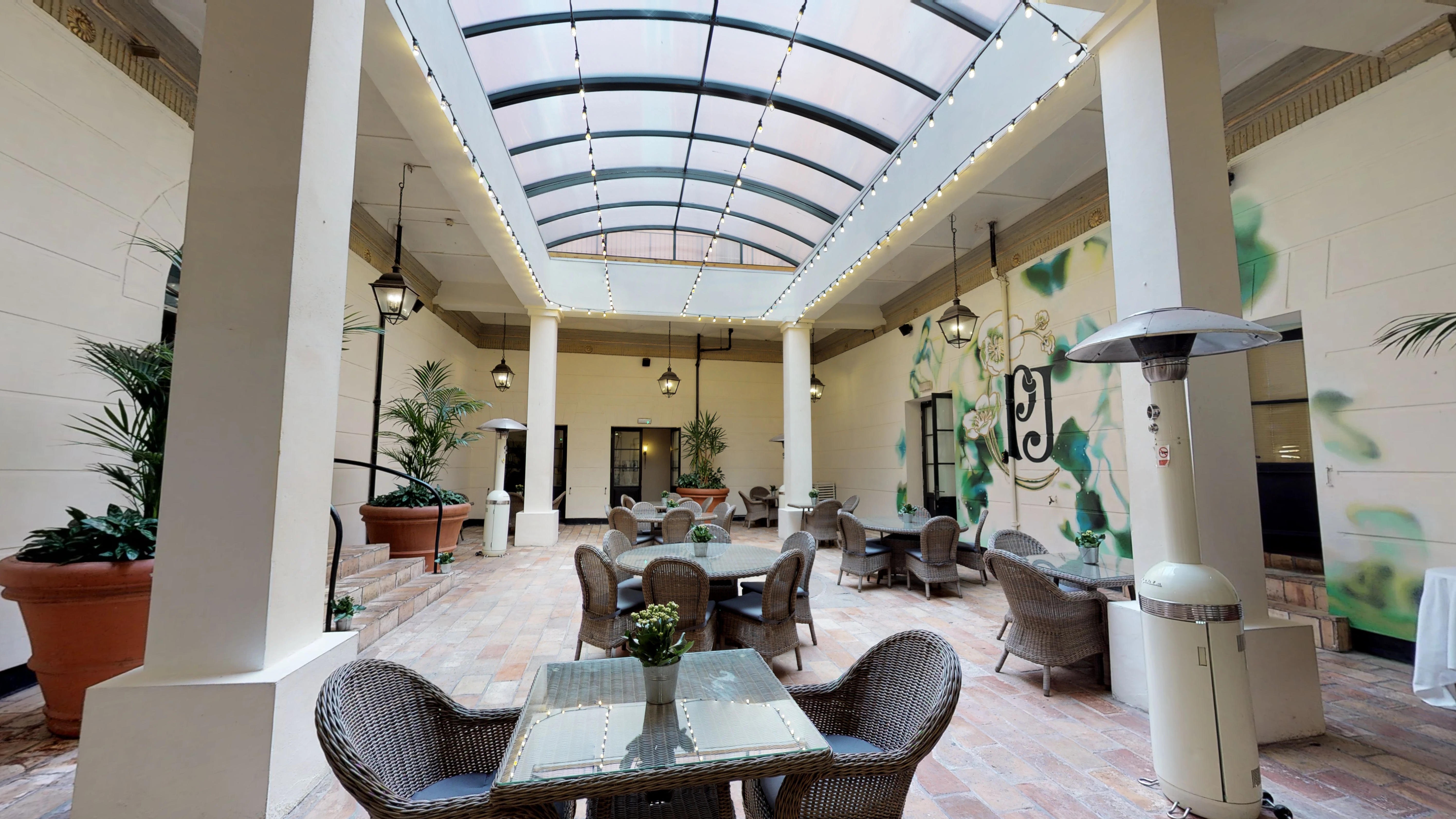 Indoor-outdoor event space at Hotel du Vin Birmingham with glass ceiling and greenery.