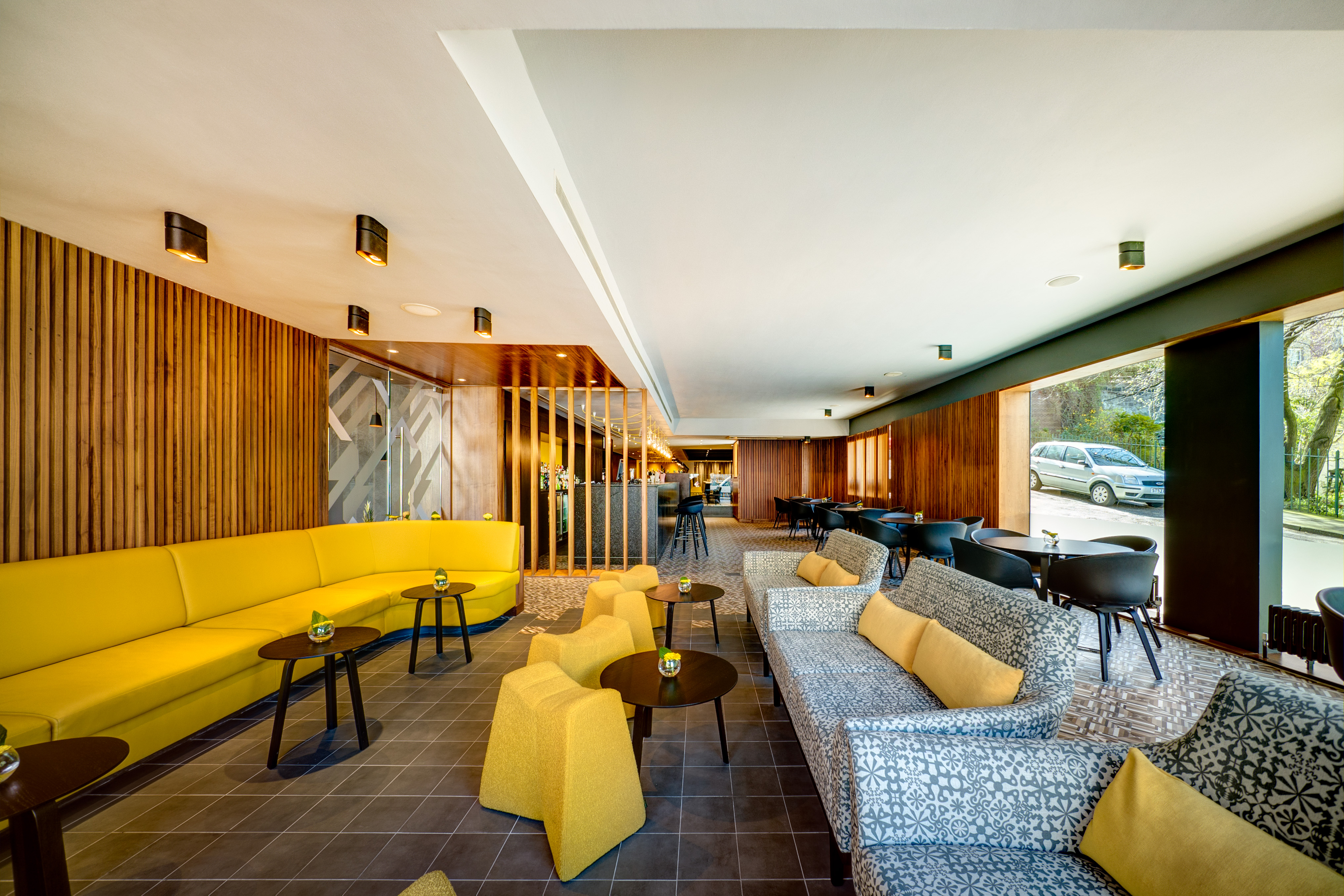 Modern lounge at Agua Restaurant, vibrant yellow seating for networking events.