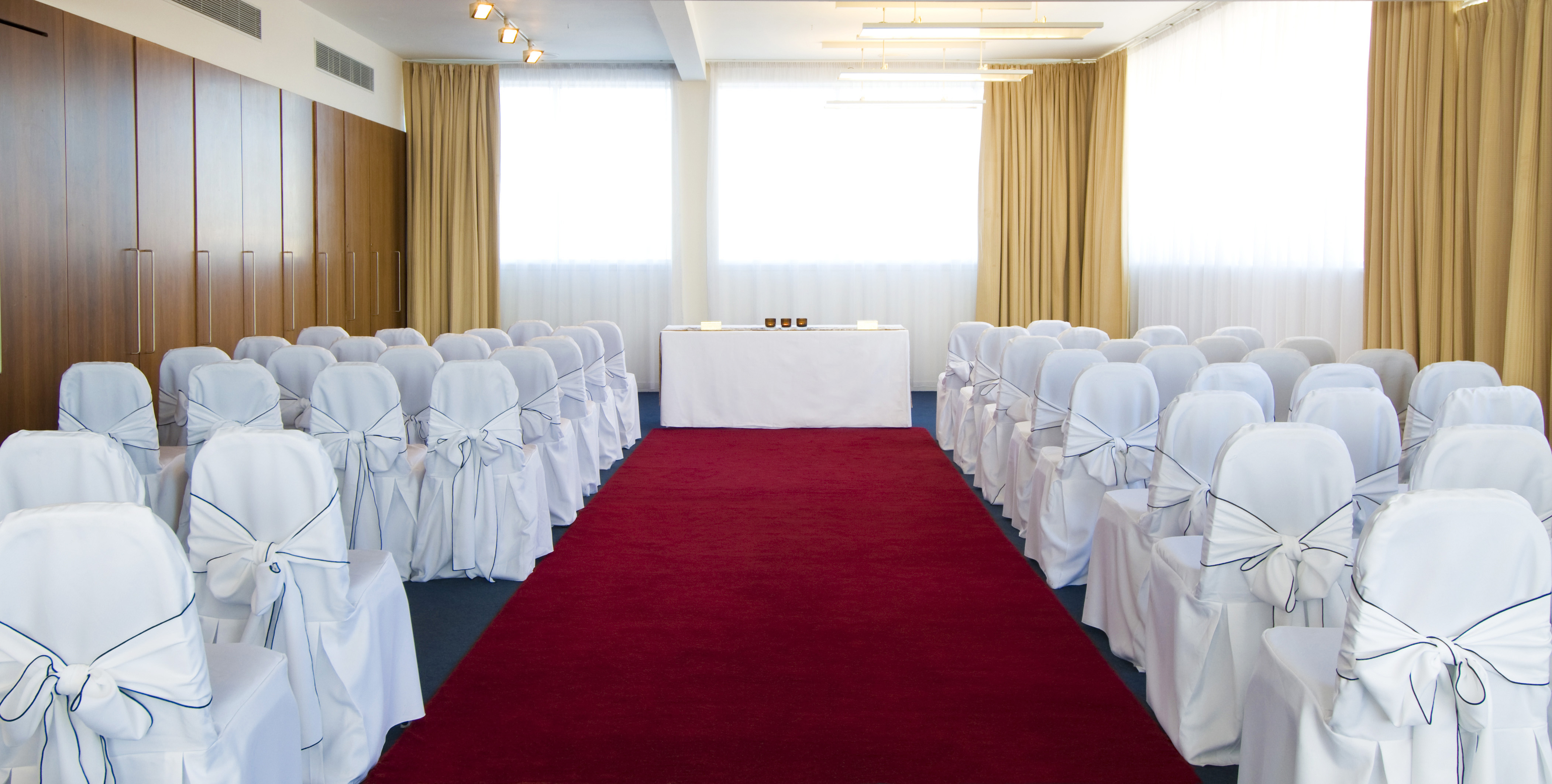 Art Gallery meeting space with white-covered chairs and red carpet, perfect for formal events.