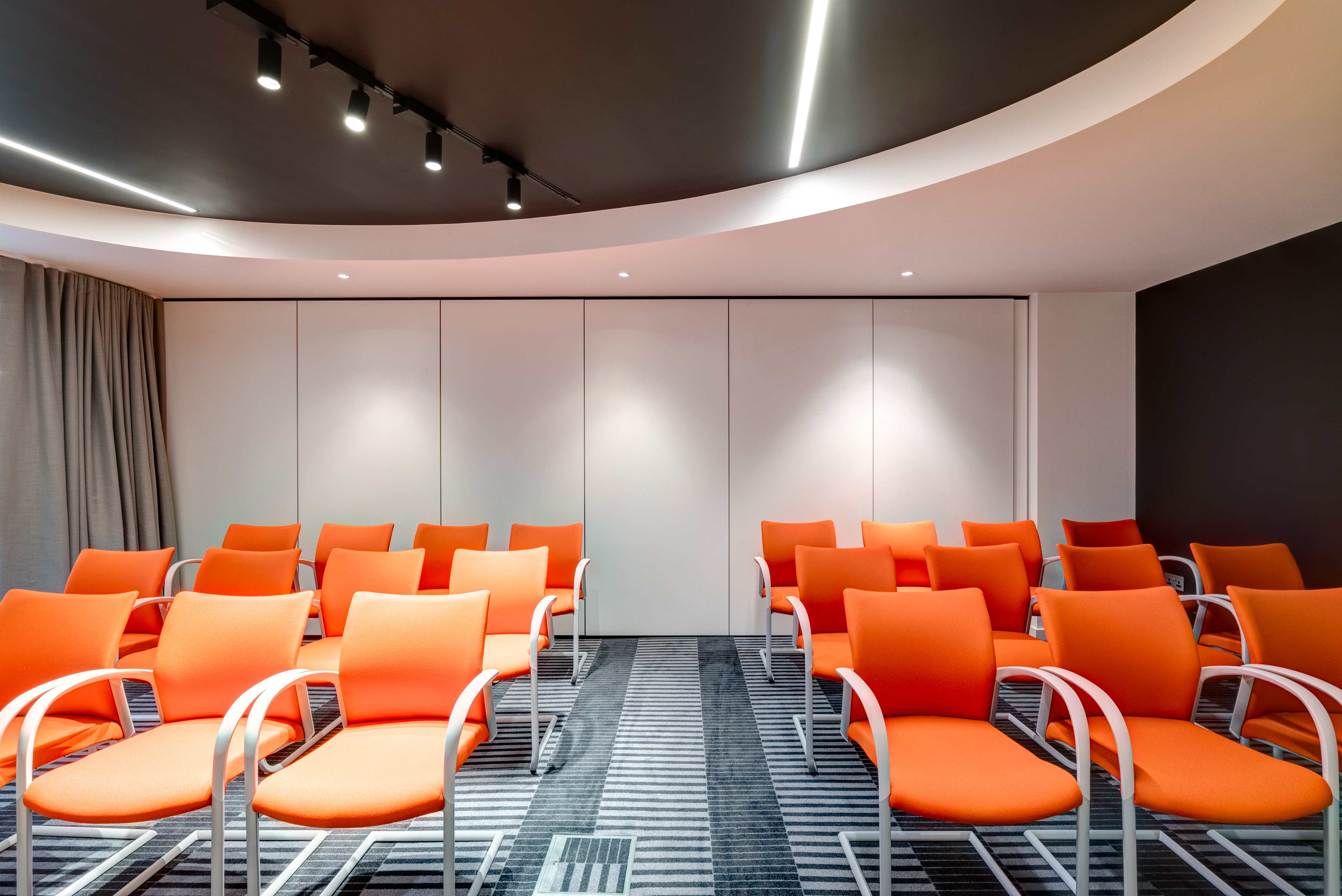 Modern meeting room with orange chairs, ideal for workshops and presentations.