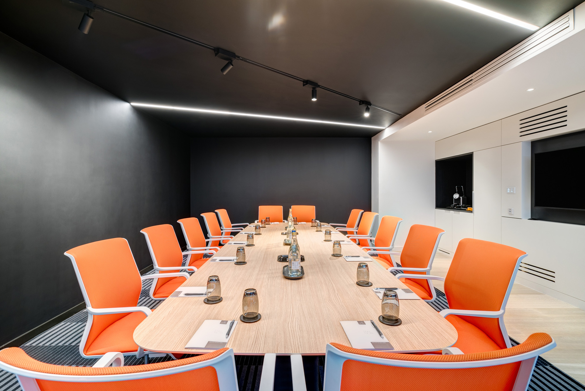 Modern meeting room in Apex City of Bath Hotel with oval table and orange chairs.