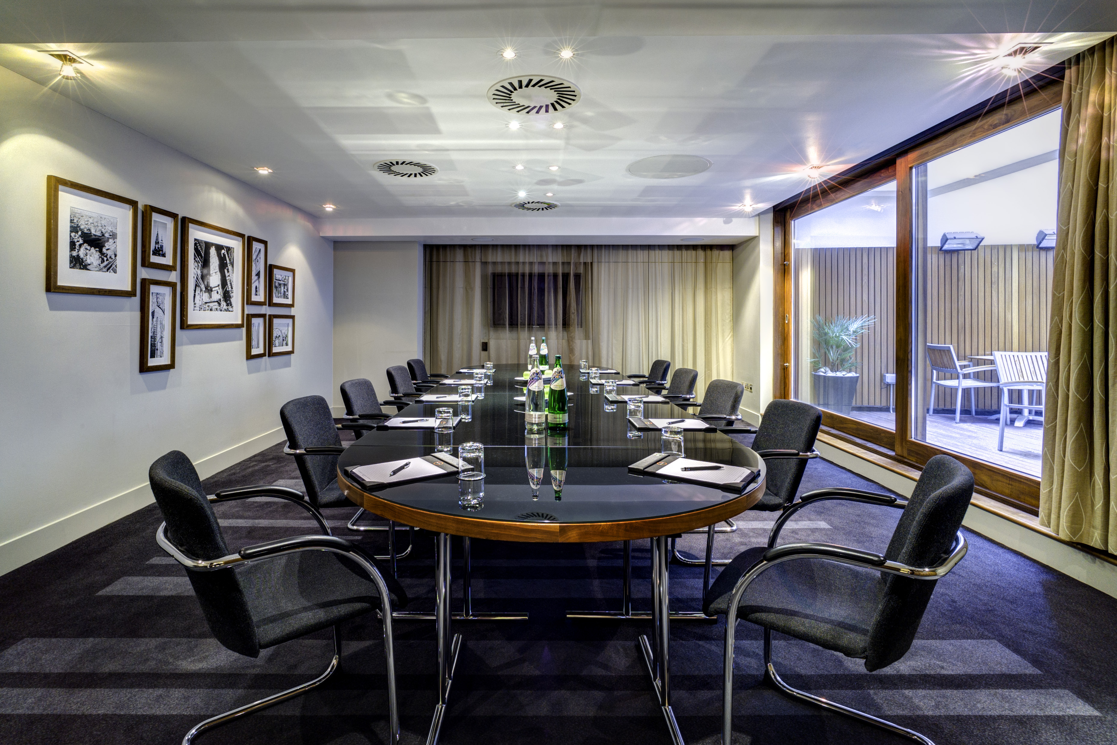 Modern meeting room in Apex City of London Hotel, featuring a sleek oval table and natural light.