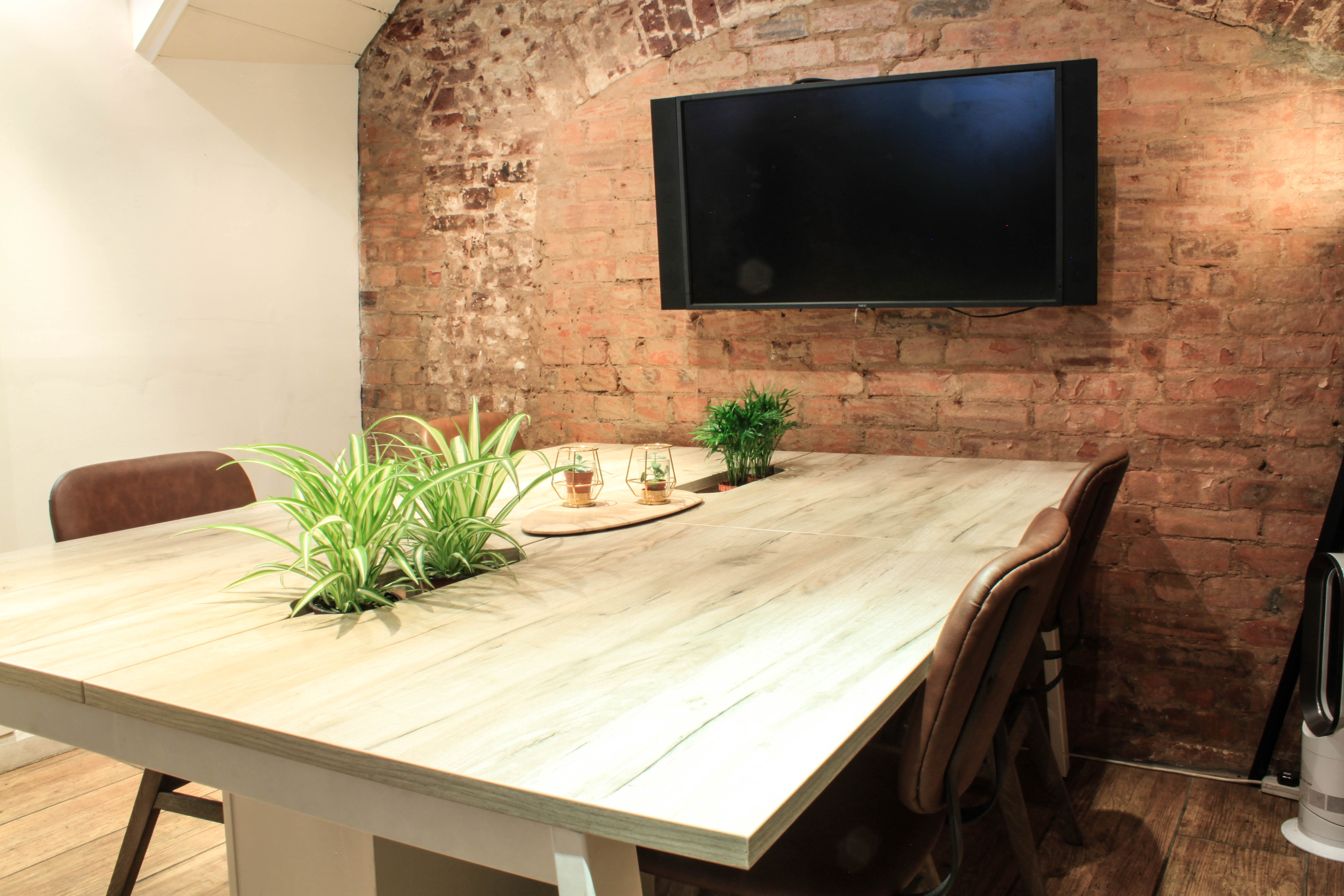 Modern meeting room with rustic brick wall, ideal for team gatherings and presentations.