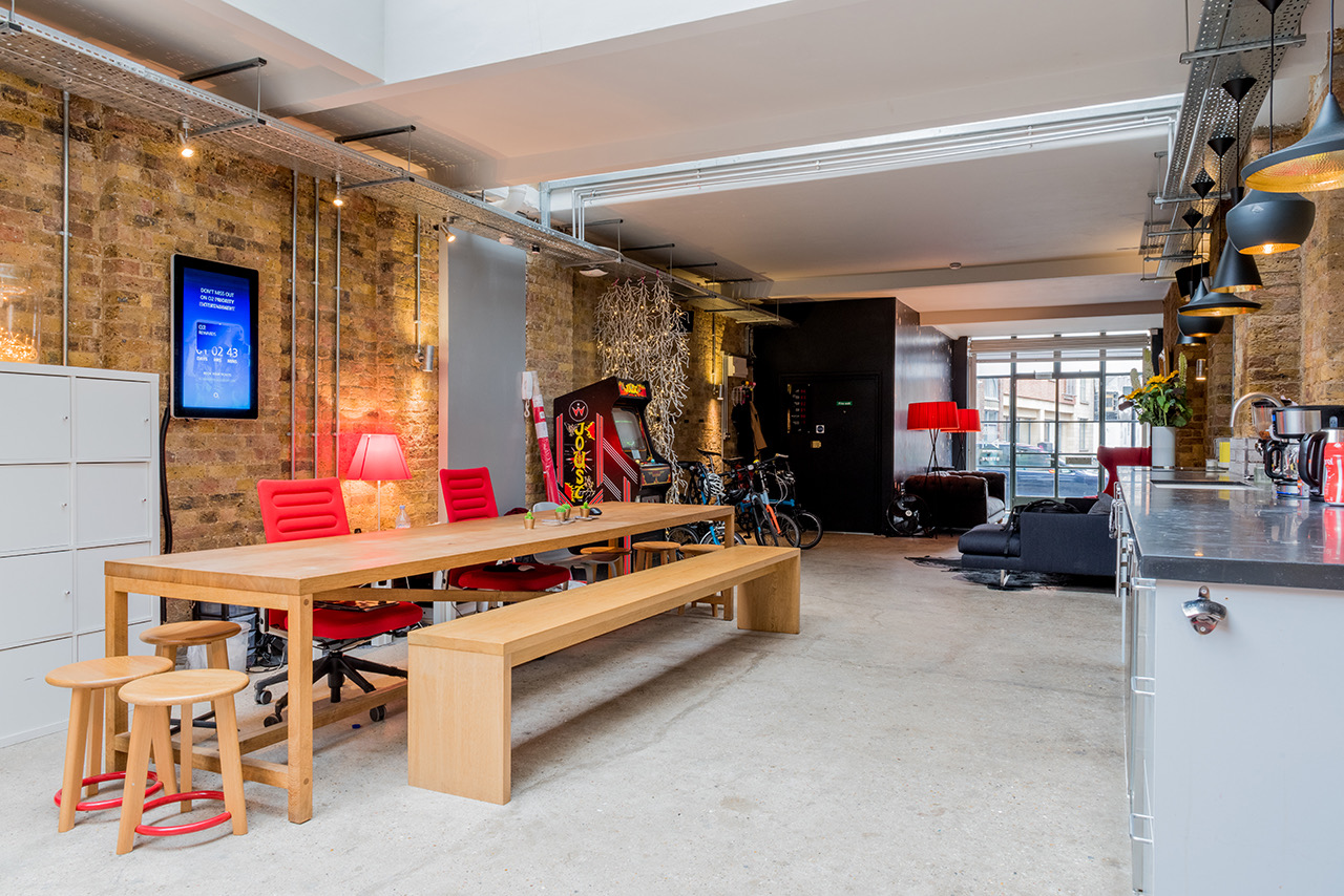 Co-sharing studio with large wooden table and vibrant red chairs for meetings and brainstorming.