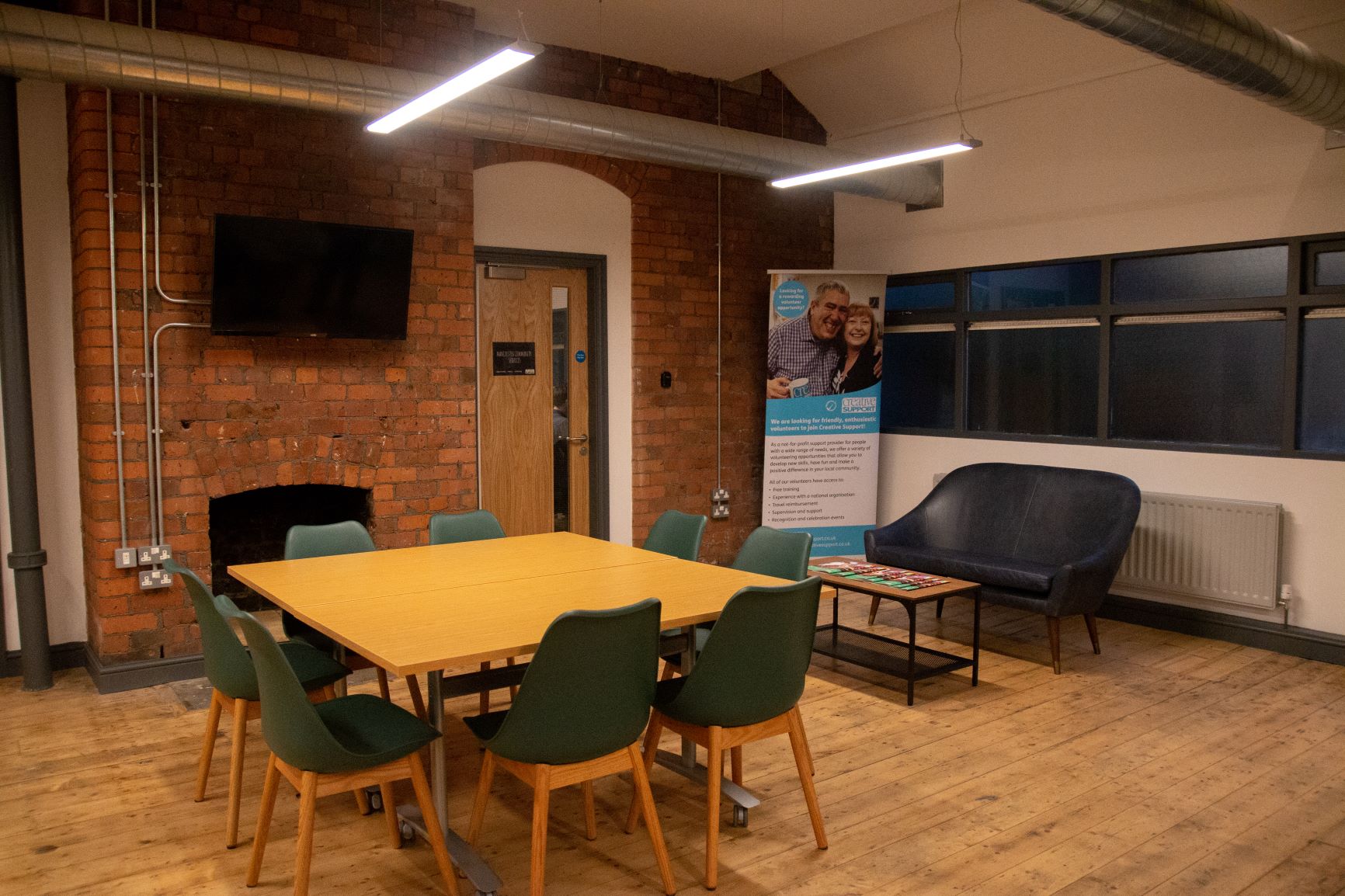 Versatile meeting space with warm brick wall, ideal for workshops and team meetings.