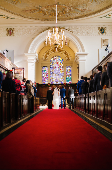 St George the Martyr Church wedding with stained glass backdrop and red carpet aisle.