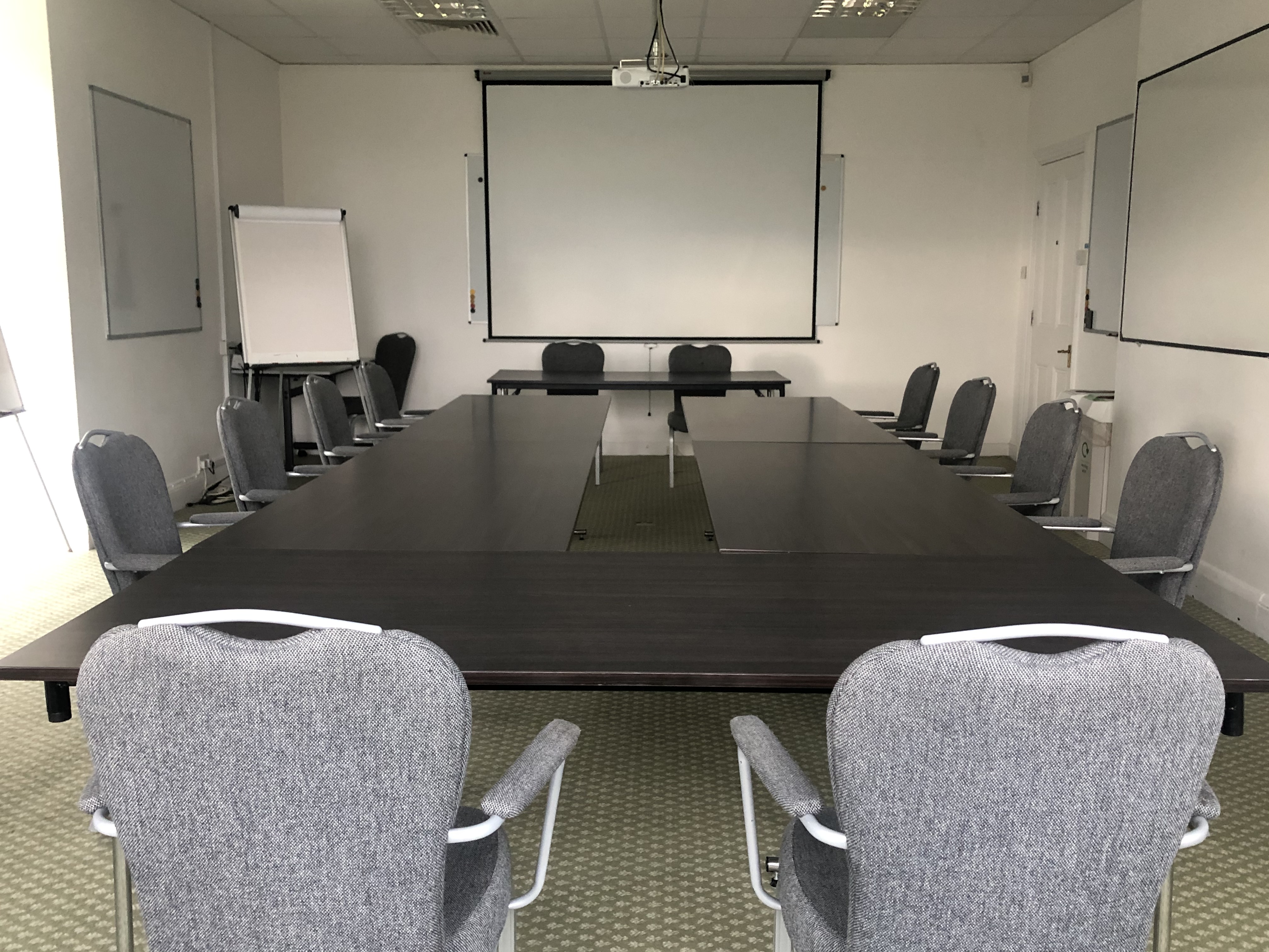 William Stokes in a professional meeting room with a large table and projector.