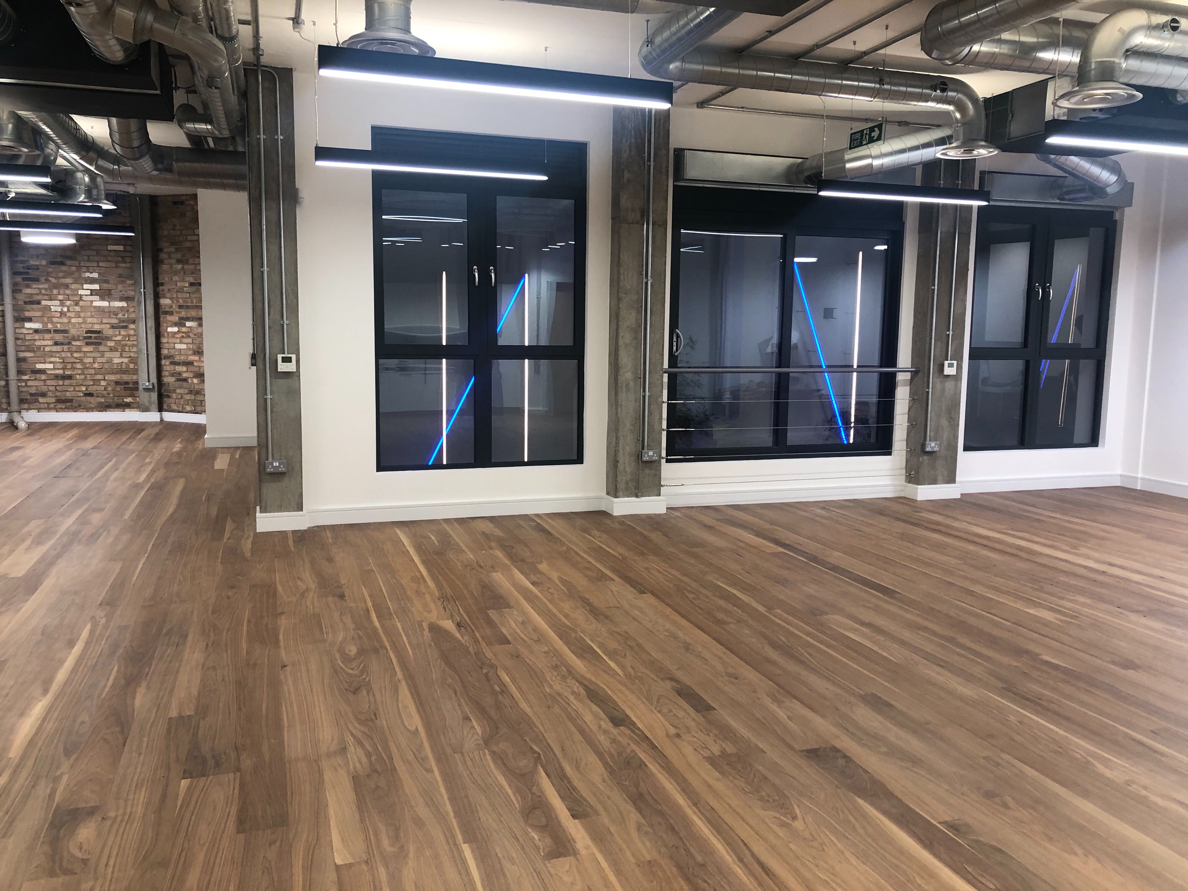 Versatile event space with large windows and wooden floor for meetings and gatherings.