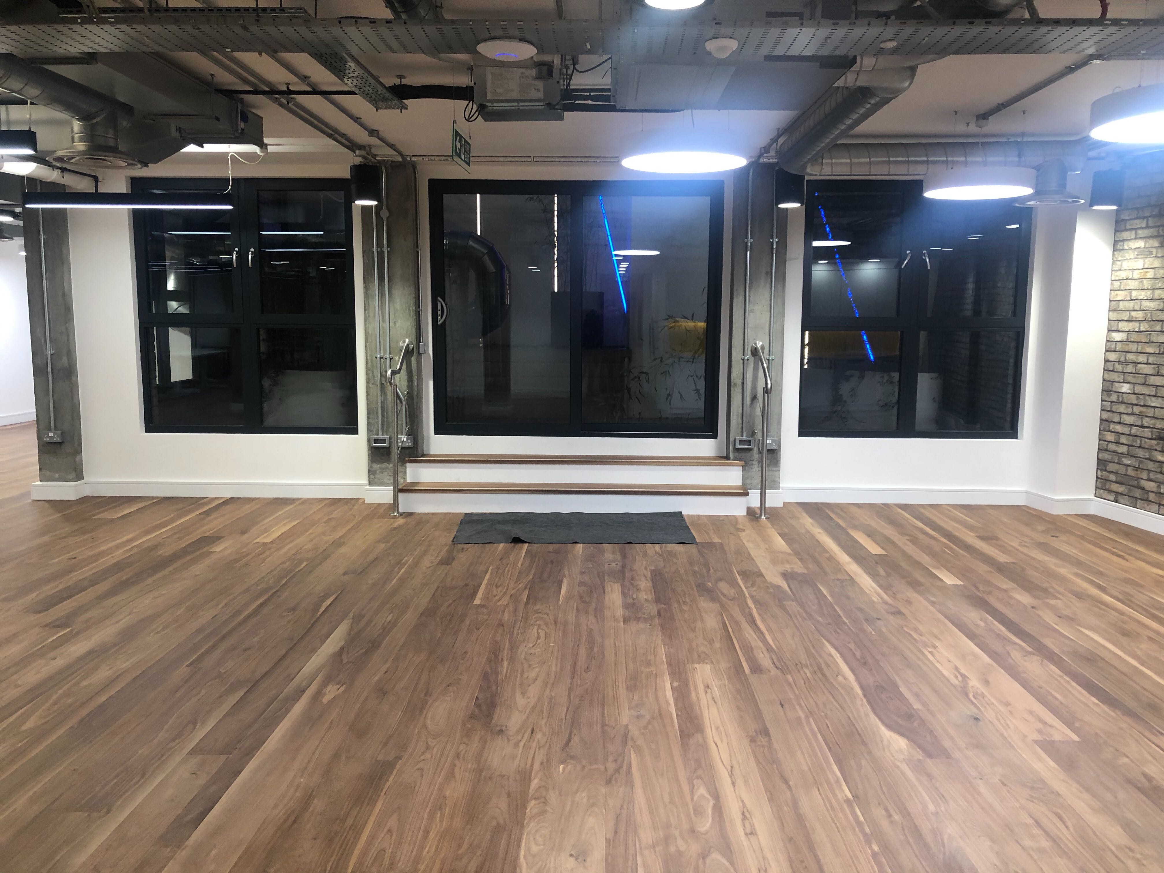 Versatile event space with large windows and wooden flooring for meetings and presentations.