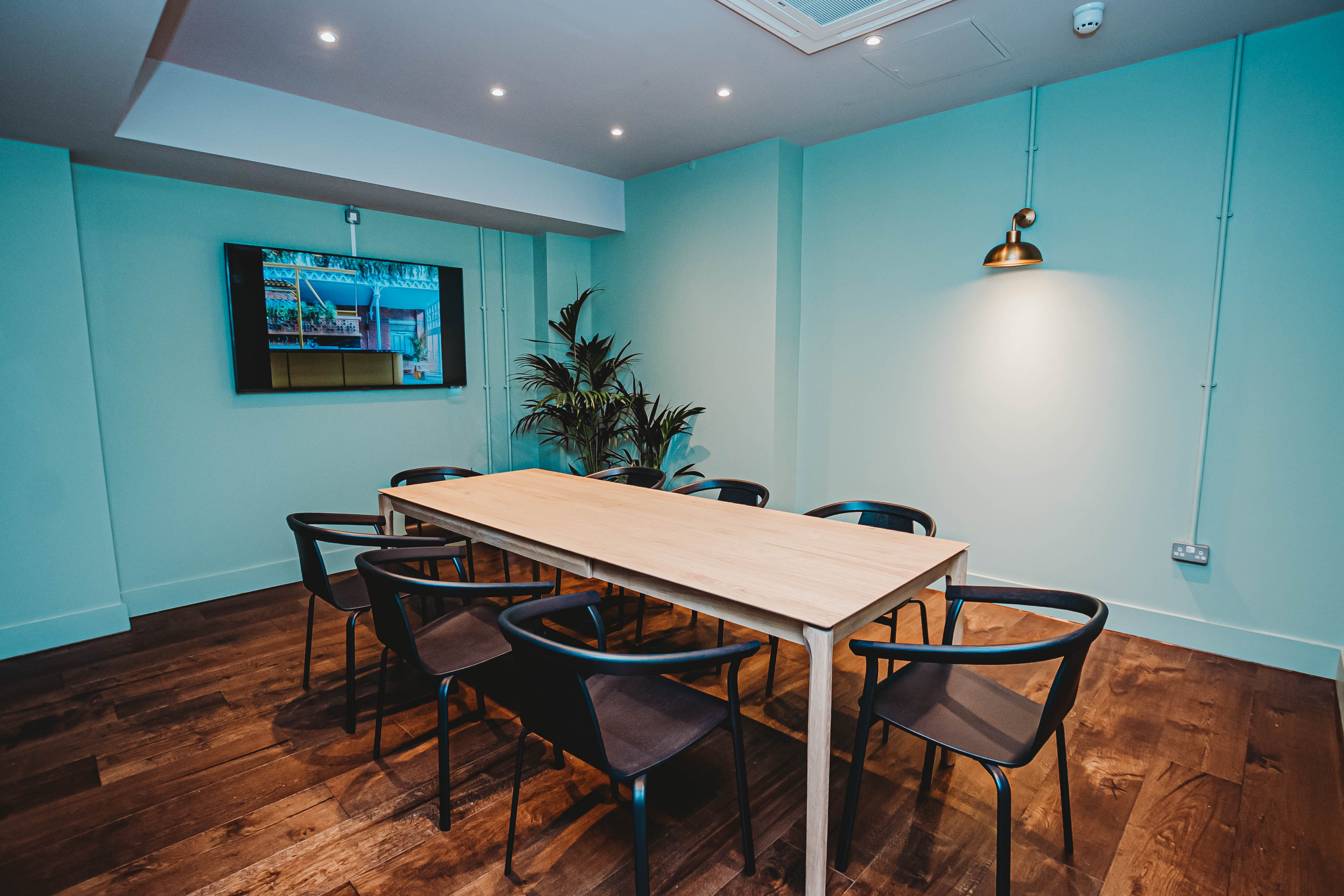 Modern meeting room with wooden table, mint-green walls for collaborative events.
