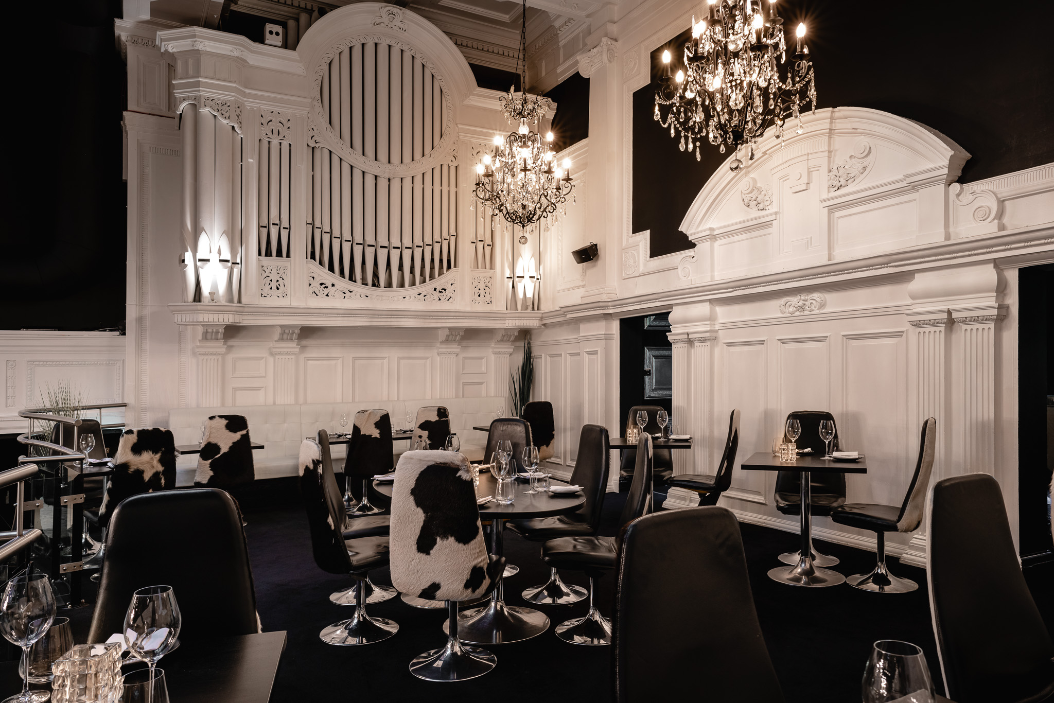 Elegant event space in Gaucho Manchester with chandeliers and organ backdrop.