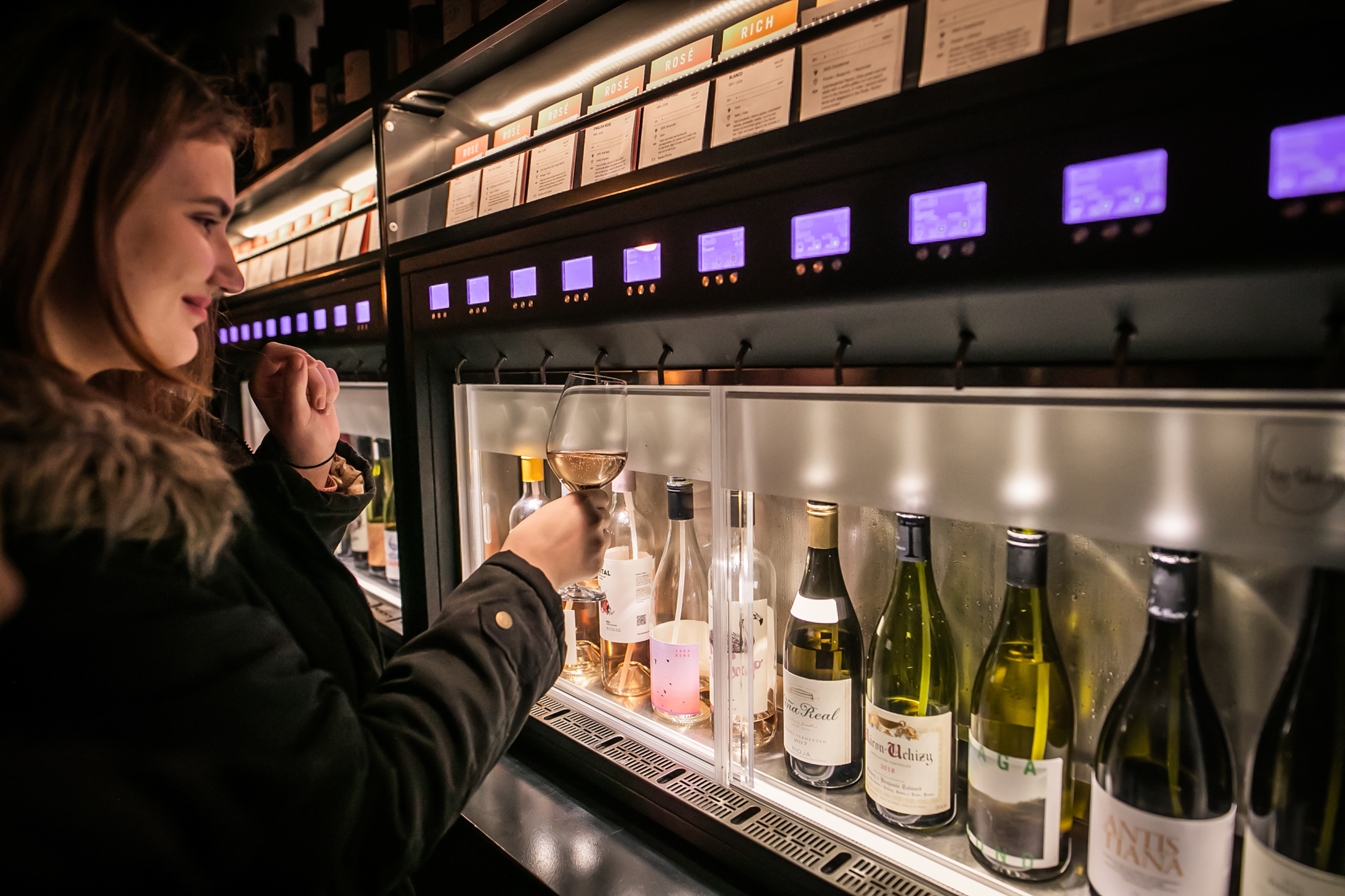 Guest using wine dispensing machine in stylish event venue at Vagabond Canary Wharf.