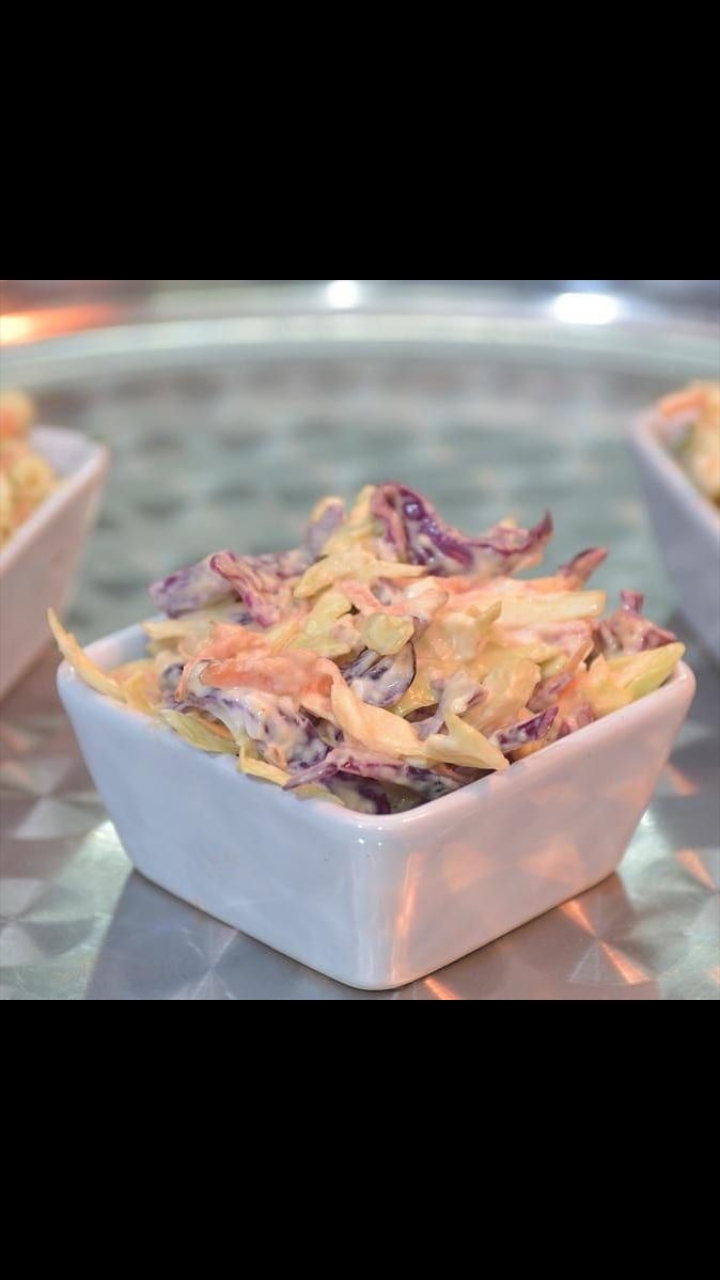 Vibrant coleslaw in a white bowl, perfect for event buffets and catering.