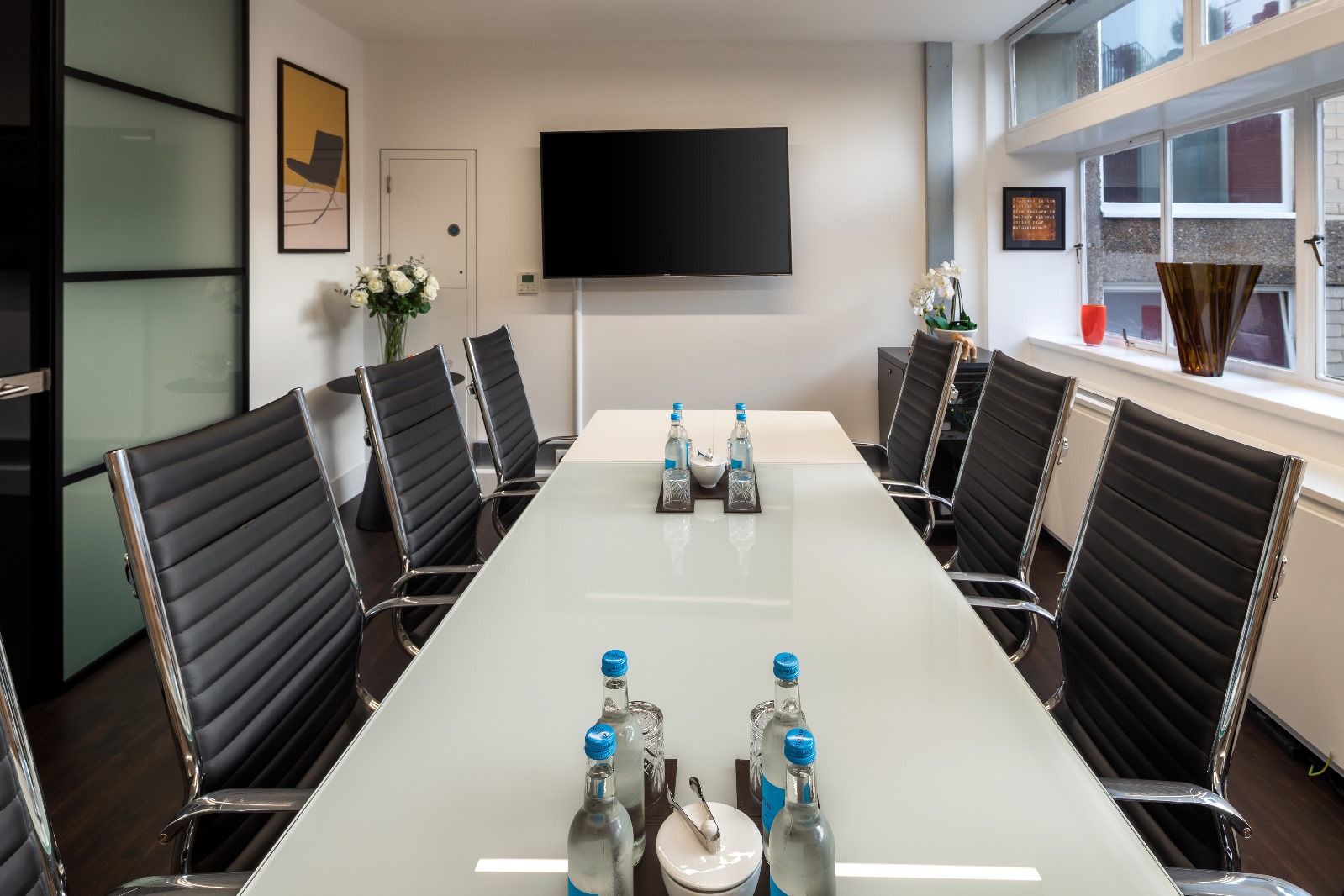 Modern conference room with glass table, ideal for meetings and strategic planning.