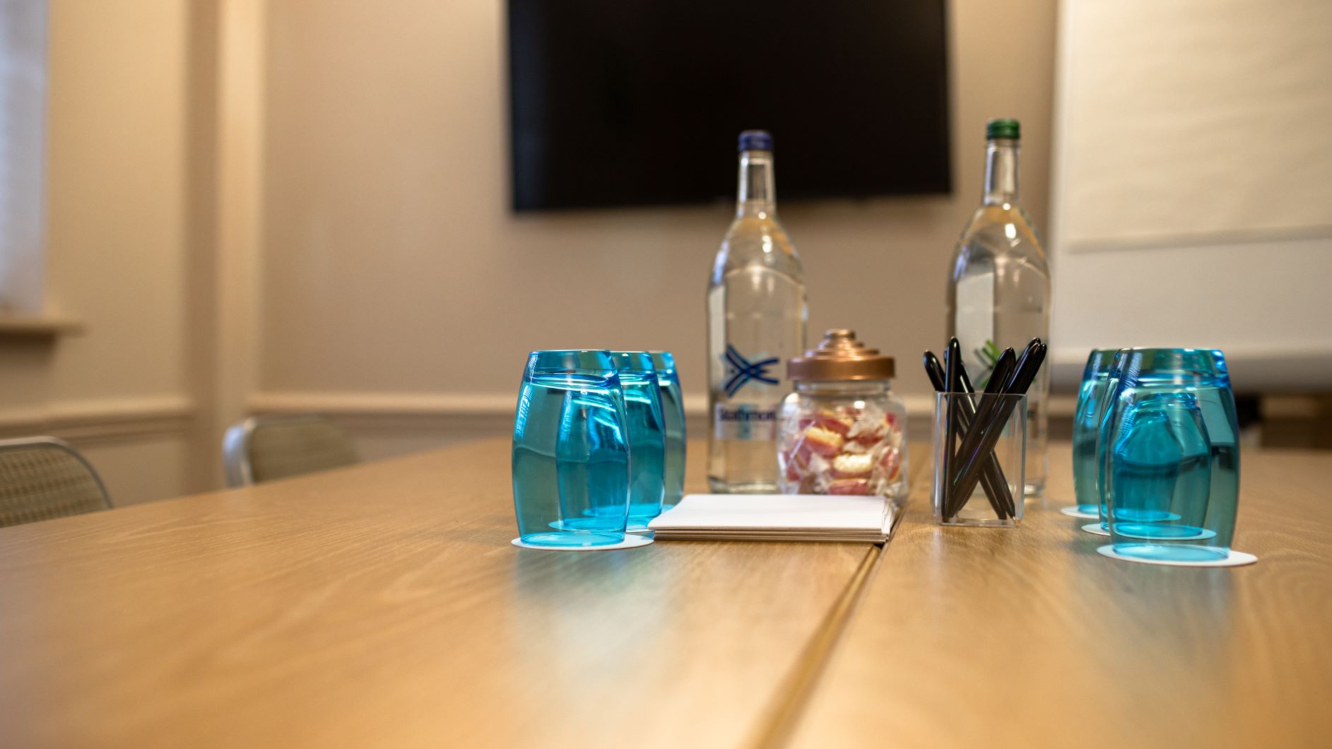 Meeting setup at voco™ Oxford Thames Hotel with polished table and vibrant glasses.