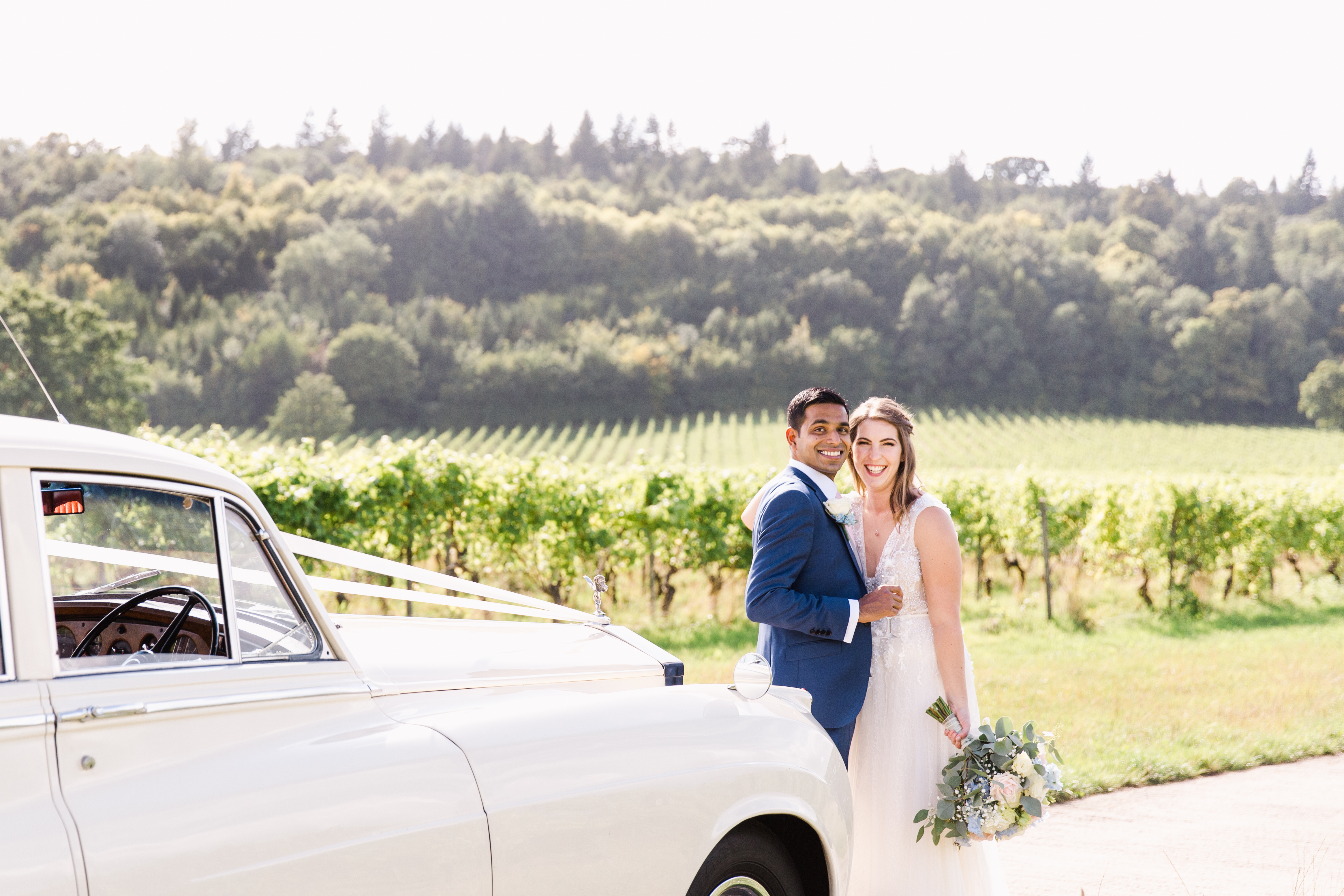 Outdoor wedding at Denbies Wine Estate with lush vineyards and vintage car.