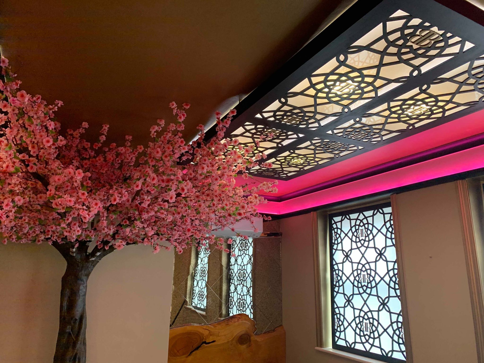 Elegant event space in Bar Beyond with cherry blossom tree and soft pink lighting.