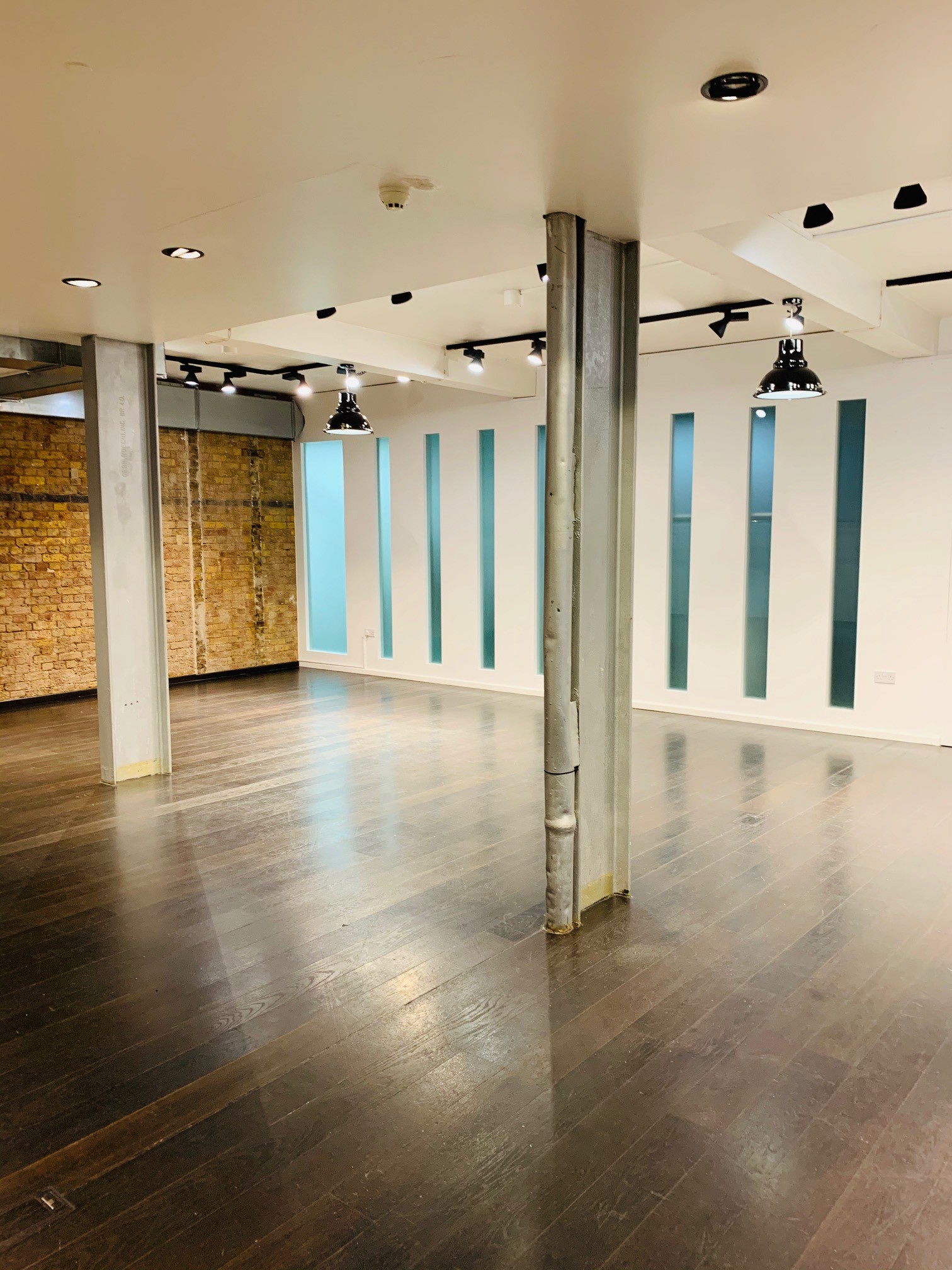 Versatile event space with polished wood floor and exposed brick for workshops in London.