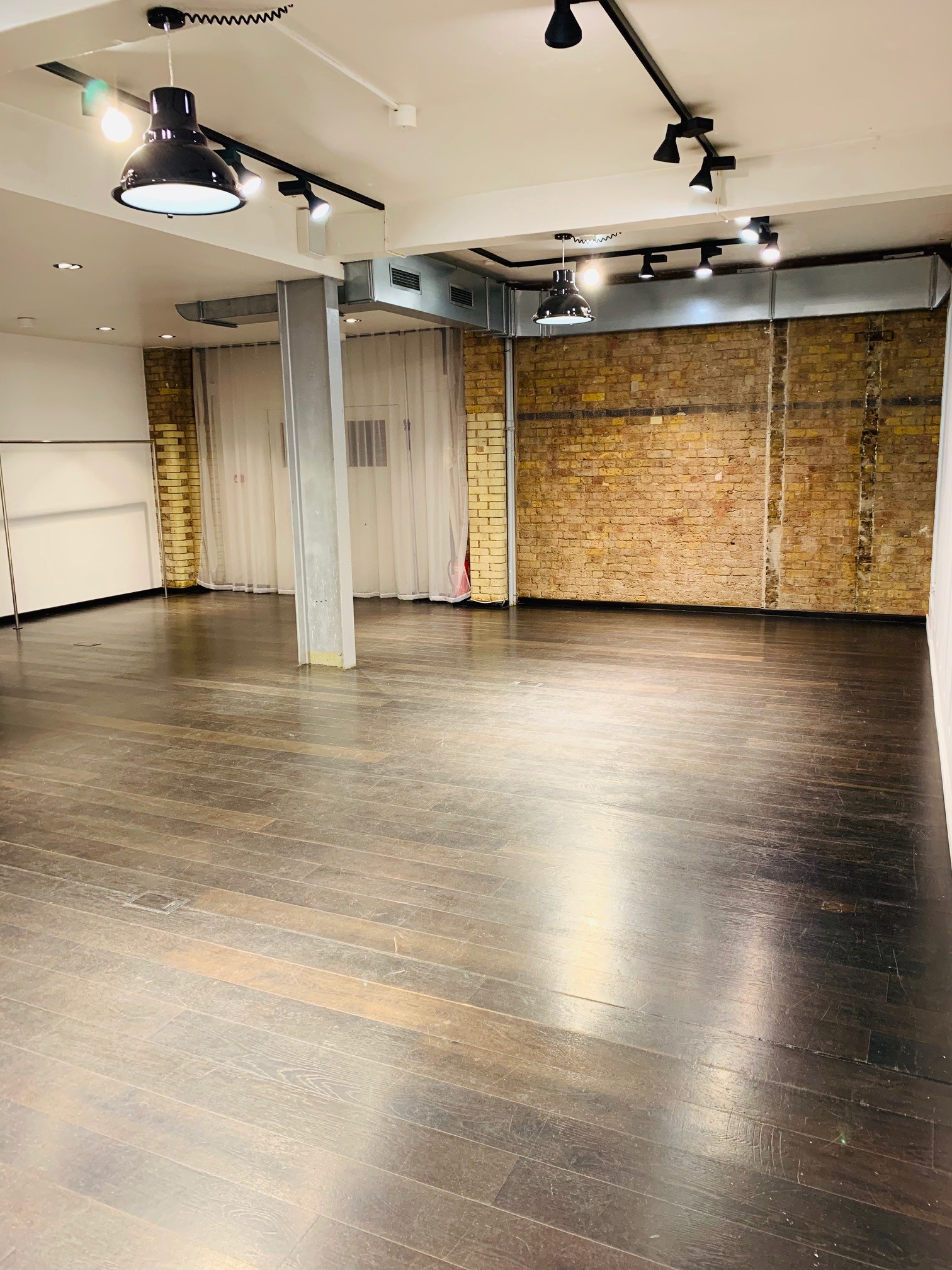 Versatile event space with wooden floors and exposed brick for workshops and gatherings.