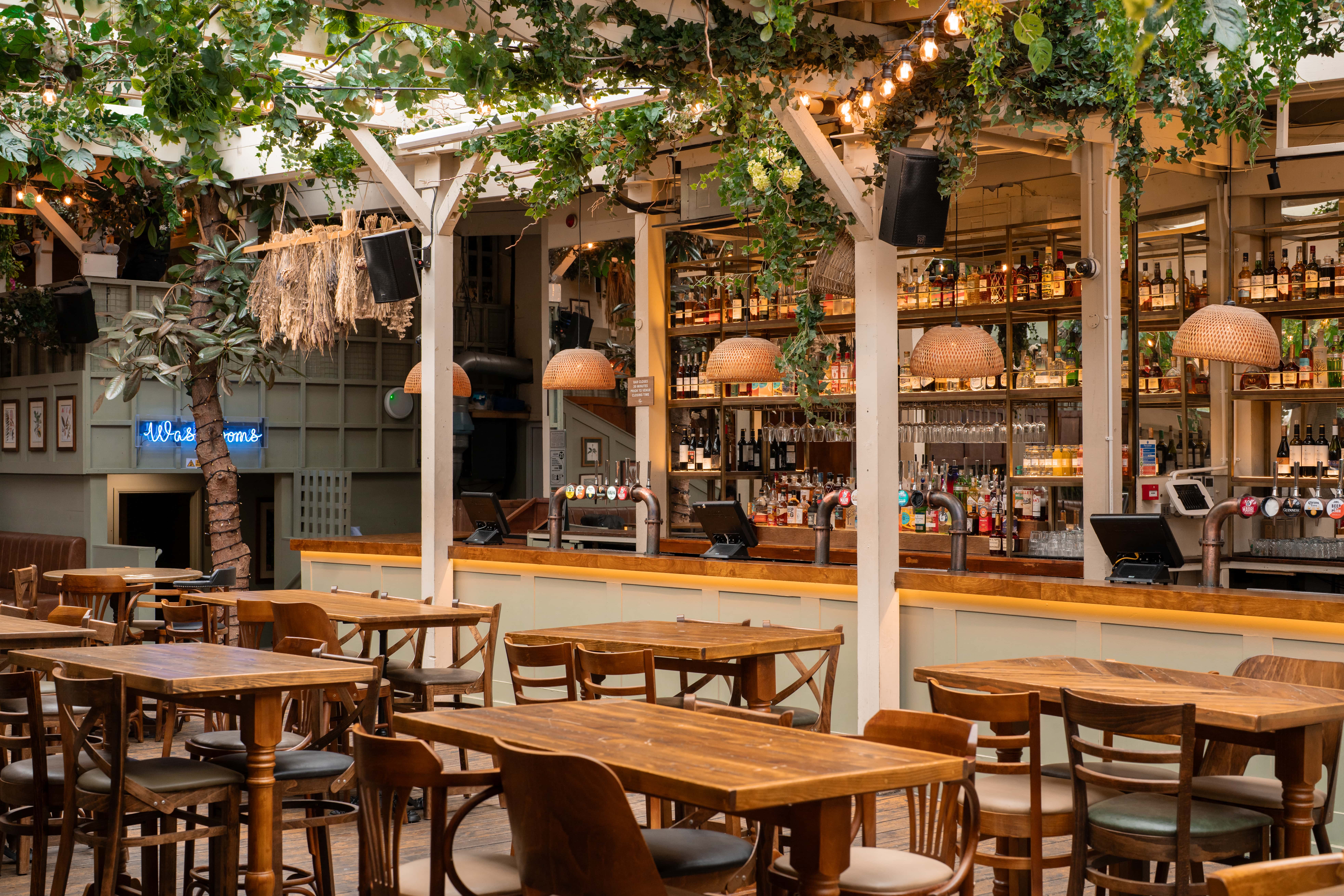 Stylish event venue with wooden tables and bar, perfect for networking and gatherings.