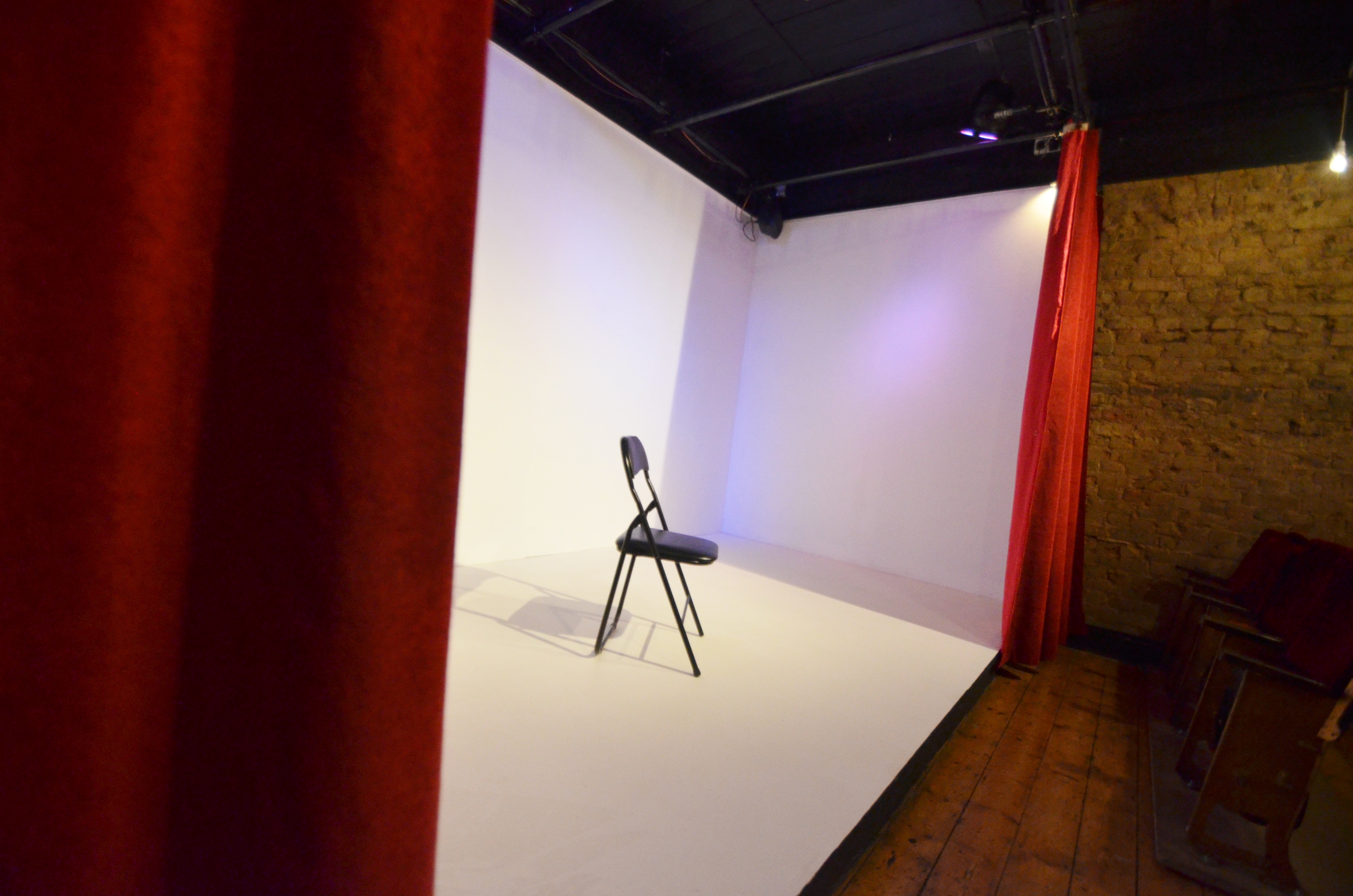 Minimalist stage with chair and red curtains, perfect for intimate presentations and events.