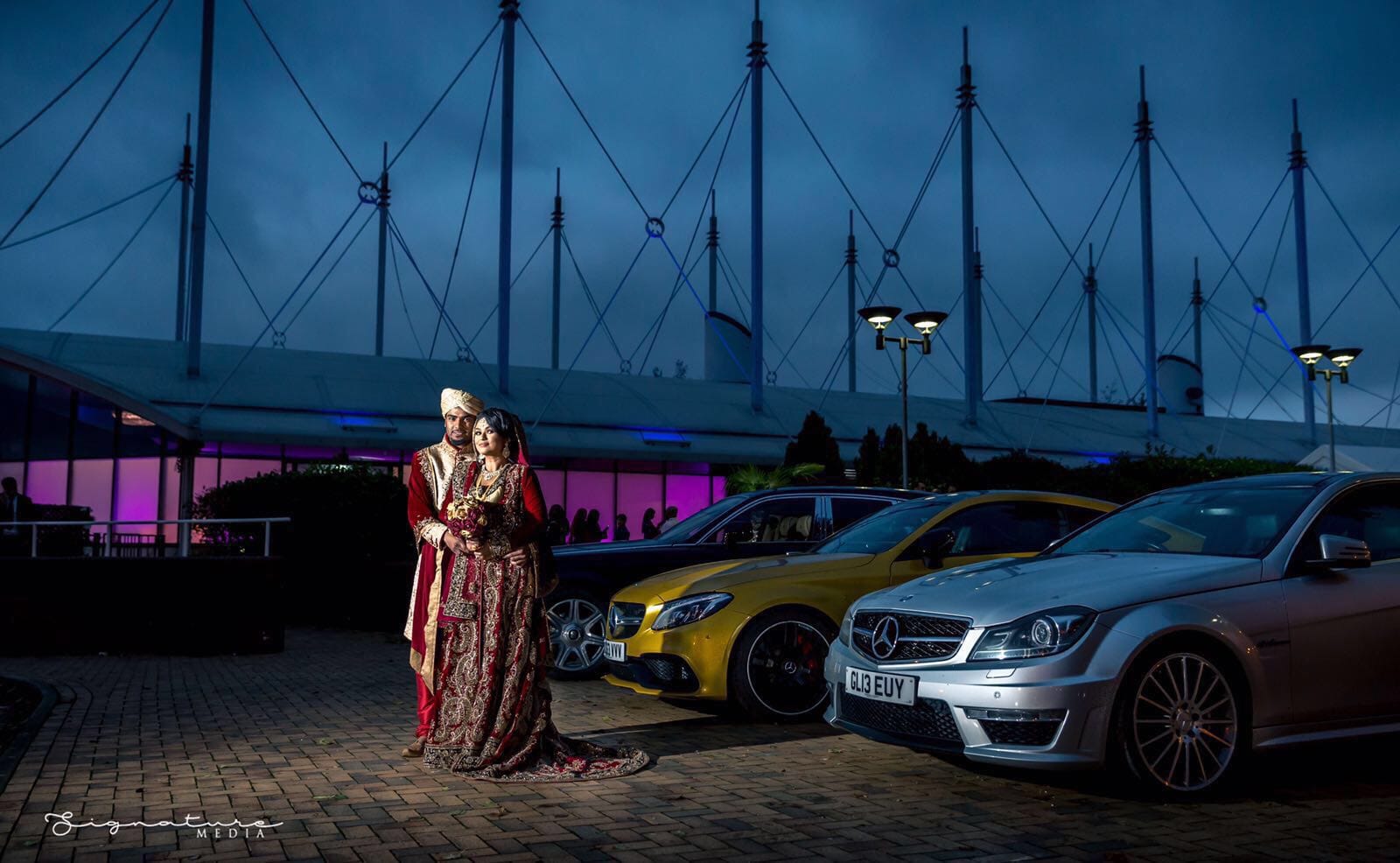 Elegant wedding in Main Hall, The Ark Royal, with couple in traditional attire and luxury cars.