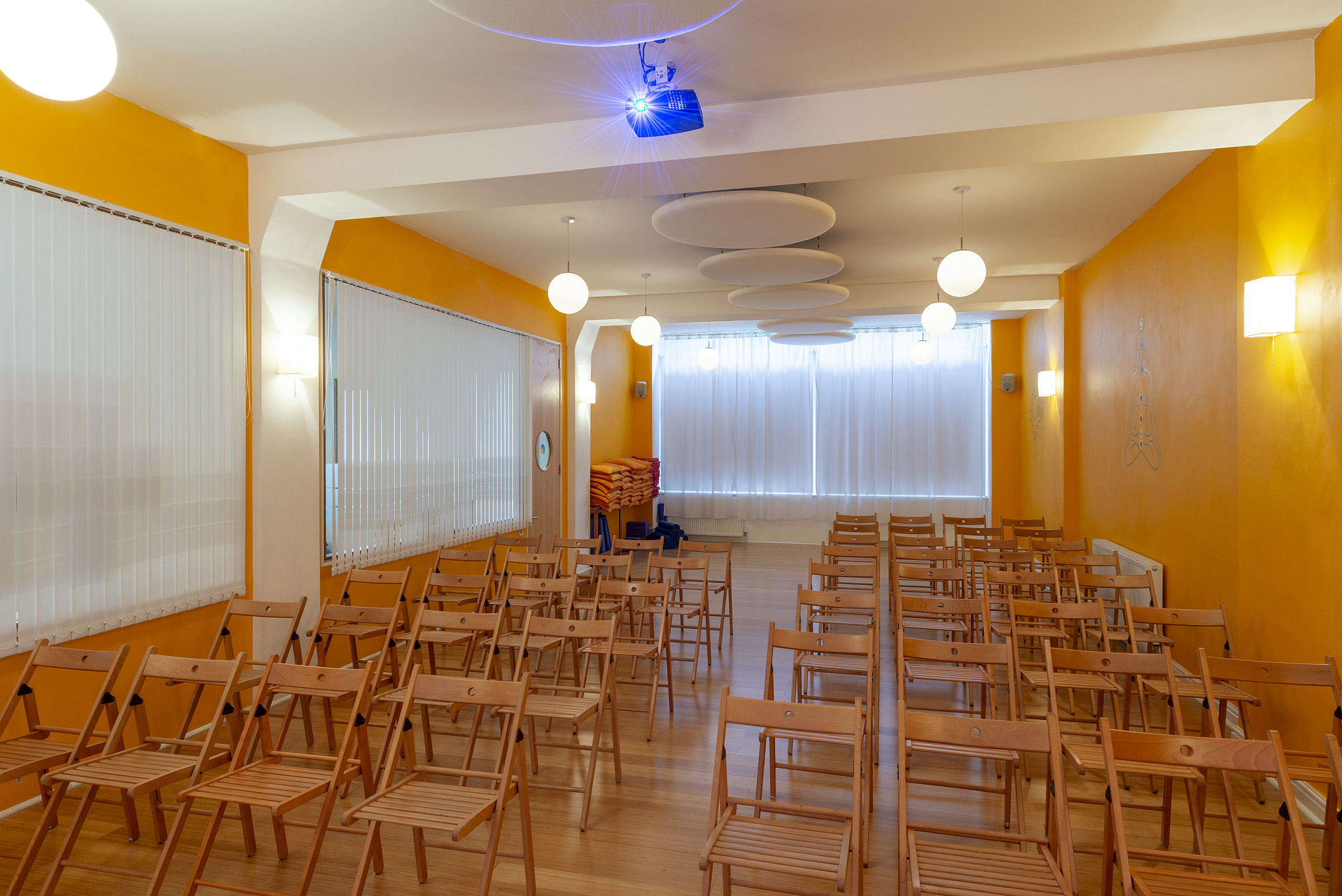 Shiva Studio at Tara Yoga Centre: versatile event space with wooden chairs for seminars.