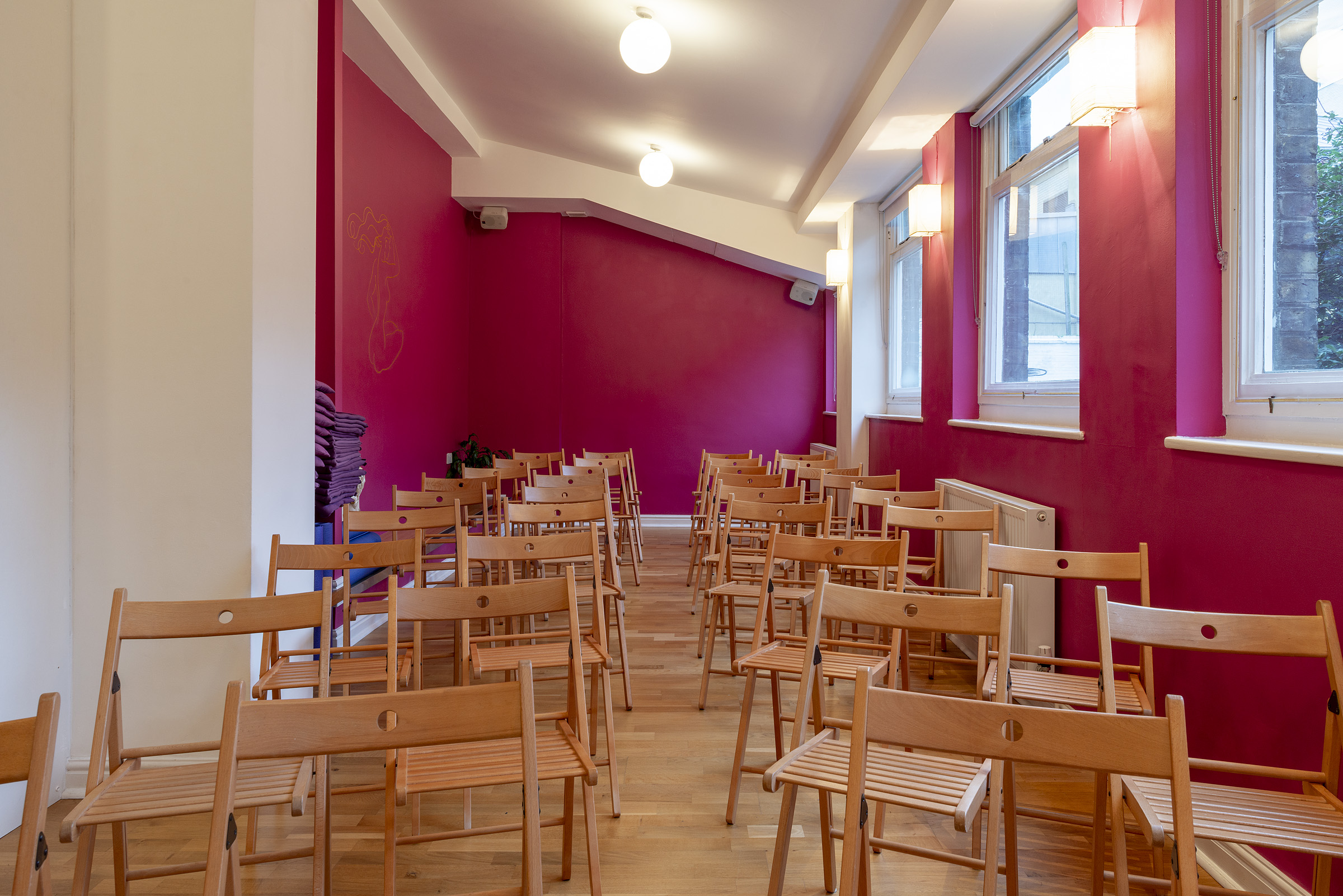 Parvati Studio at Tara Yoga Centre: vibrant pink wall, ideal for workshops and gatherings.