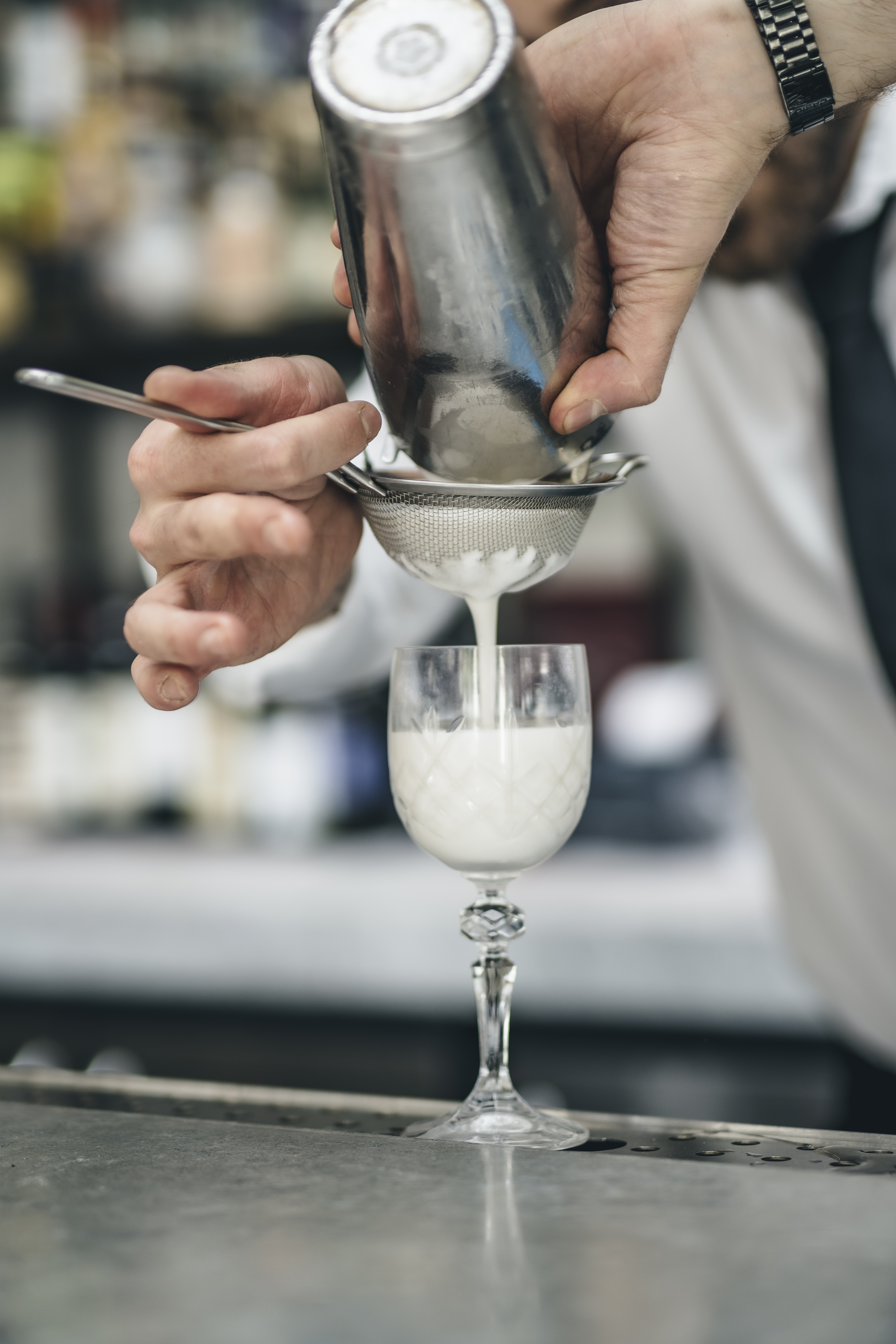 Bartender straining cocktail at TOZI Restaurant & Bar for elegant event catering.
