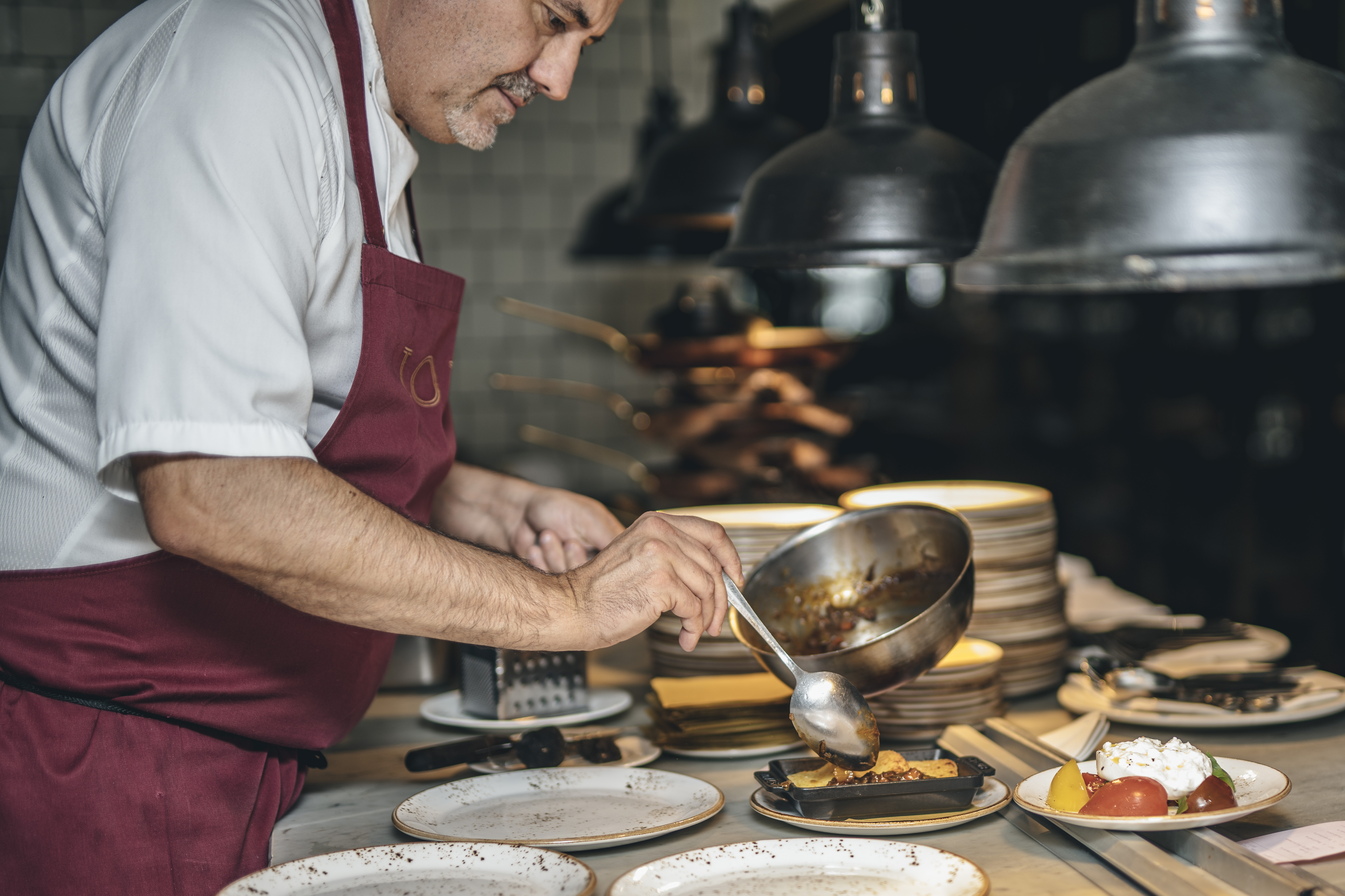 Chef plating a dish at TOZI Restaurant & Bar for exclusive culinary events.