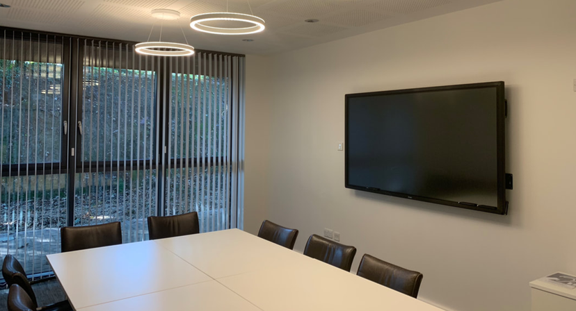 Modern meeting room with large screen and natural light at Aldingbourne Country Centre.