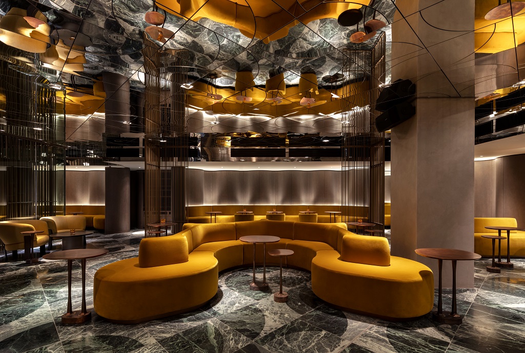 Modern event space in The Londoner with curved yellow seating and marble floor.