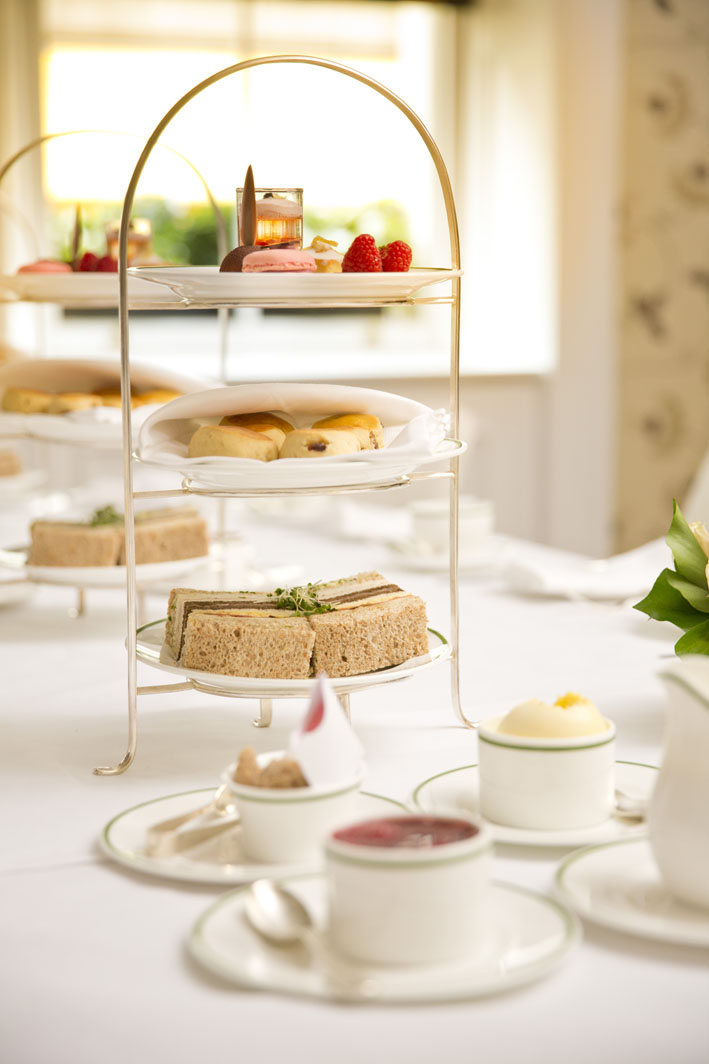 Elegant tiered stand with sandwiches and scones for afternoon tea event.