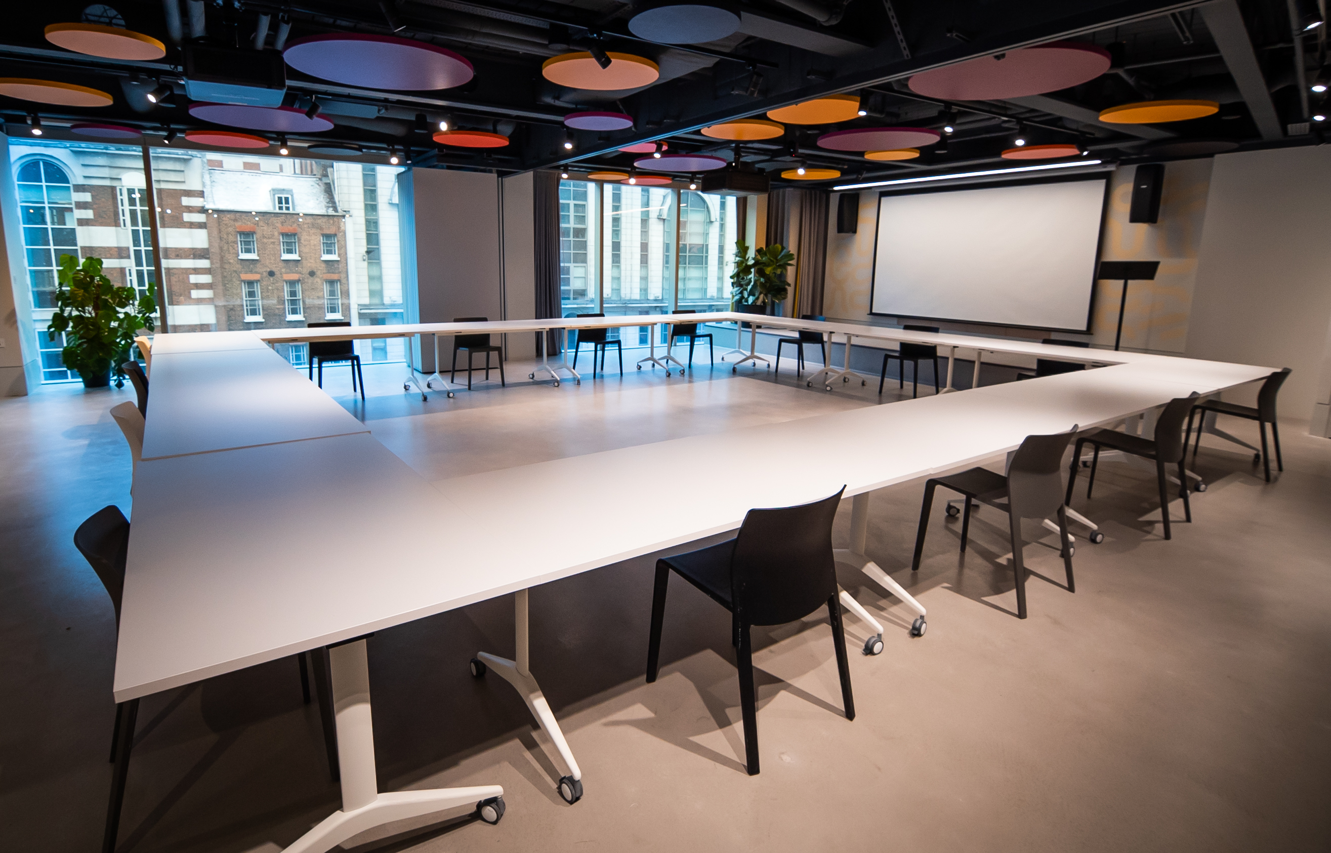 Modern business lounge with U-shaped table for meetings and workshops.