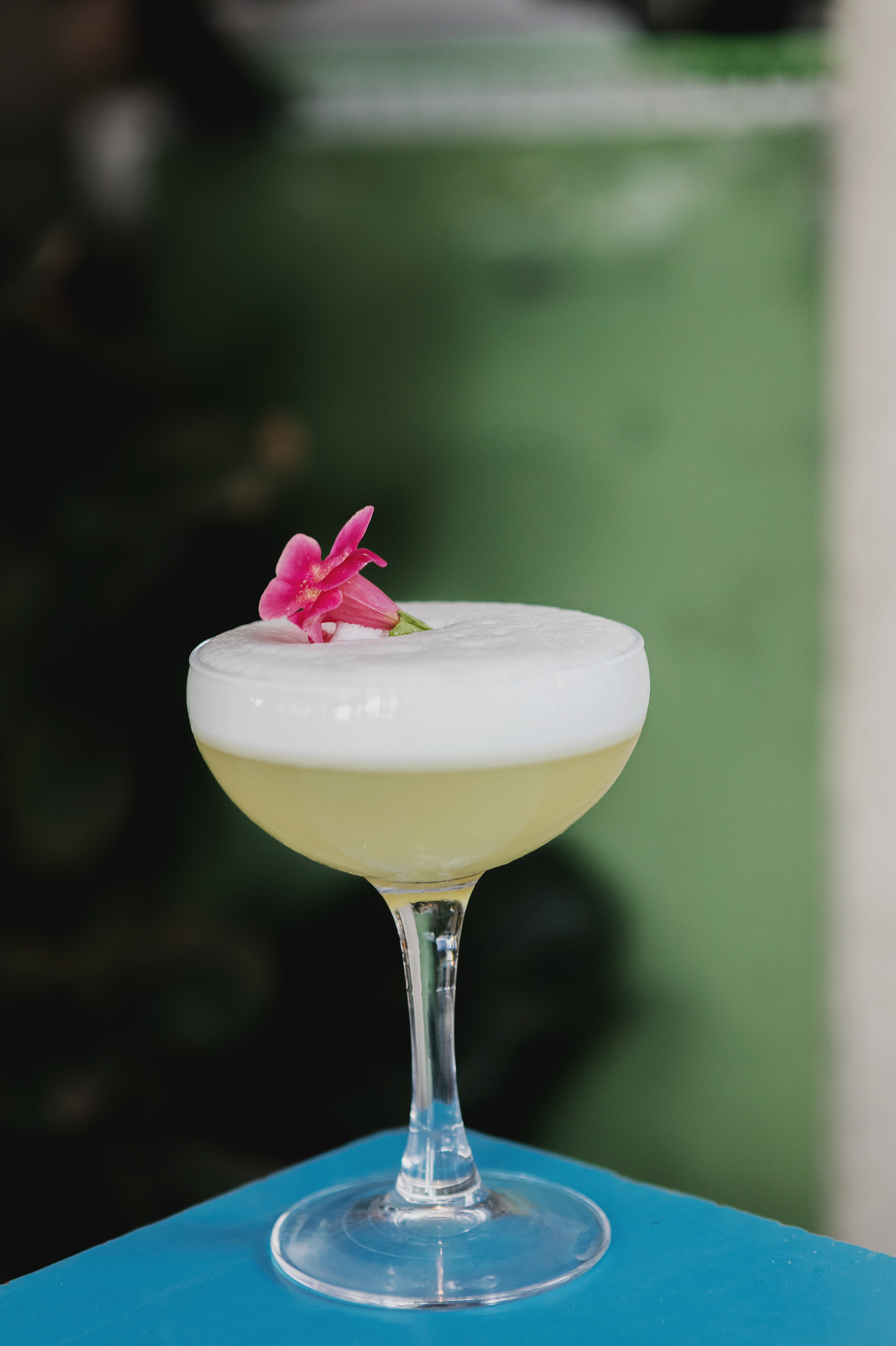Elegant cocktail with frothy top and pink flower garnish at Heist Bank event venue.