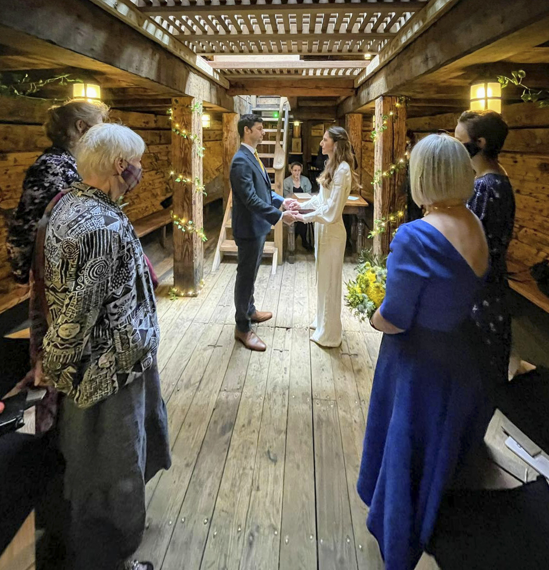 Intimate wedding ceremony in rustic wooden venue, warm lighting, unique event space.
